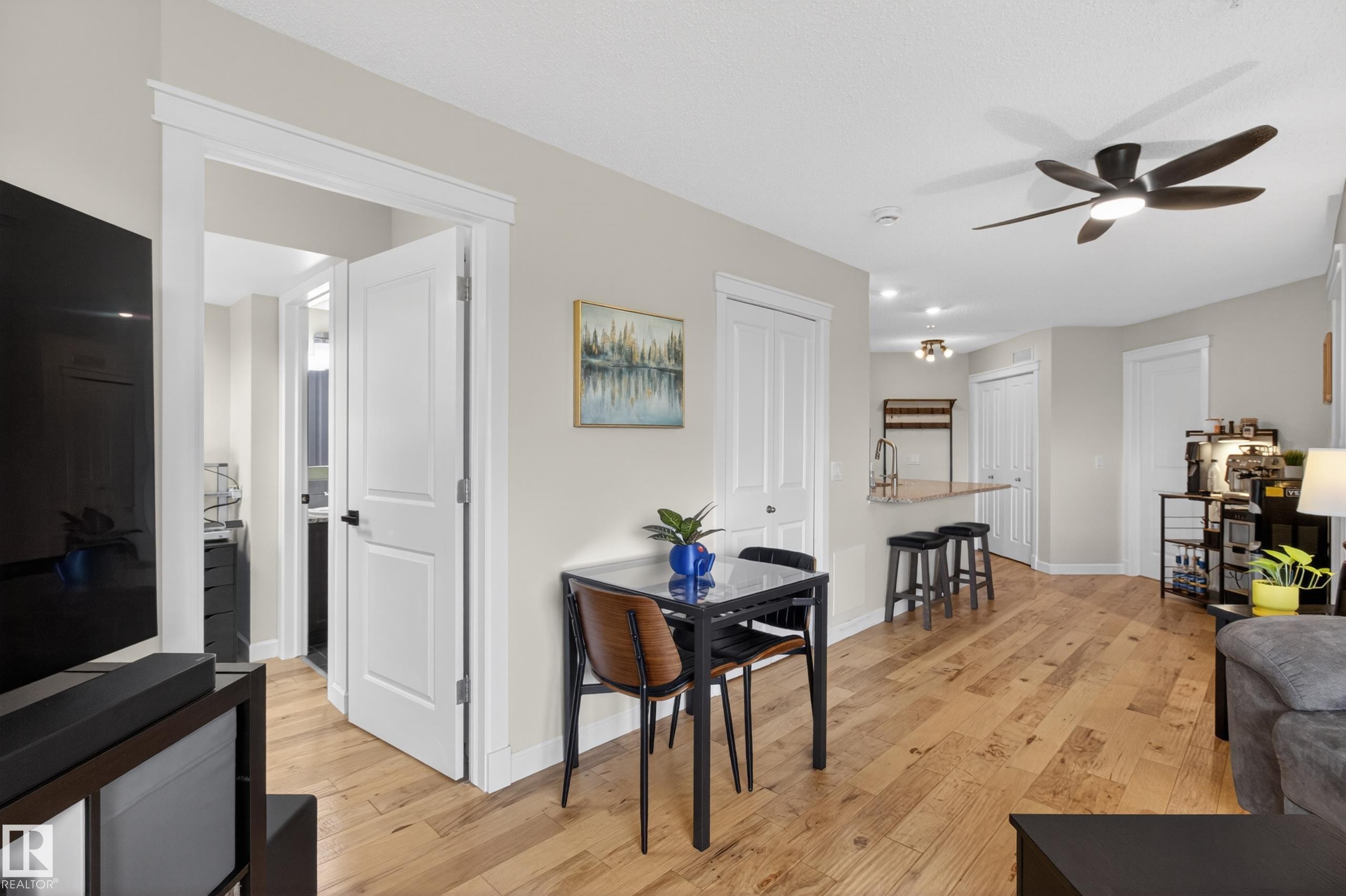 Open-concept living space featuring wood-finish flooring, a modern ceiling fan, and a light color palette - 211 3719 Whitelaw Lane, Edmonton, AB