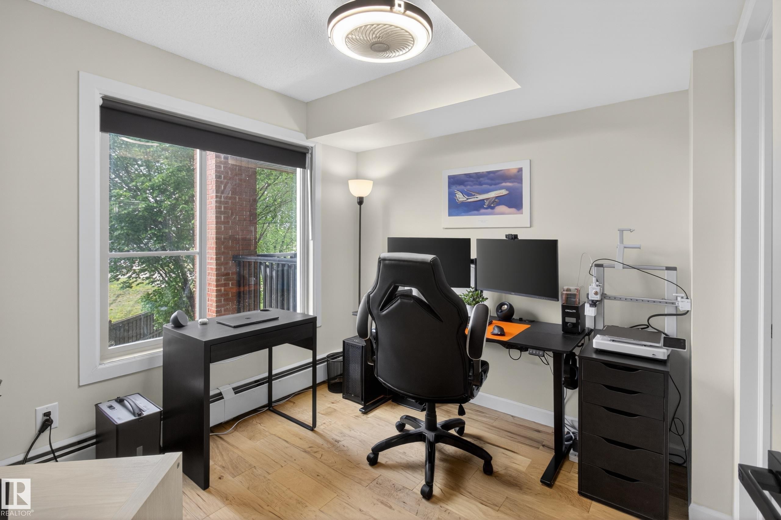 Room featuring a large window, light wood-finish flooring, neutral wall color, and a ceiling-mounted light fixture - 211 3719 Whitelaw Lane, Edmonton, AB