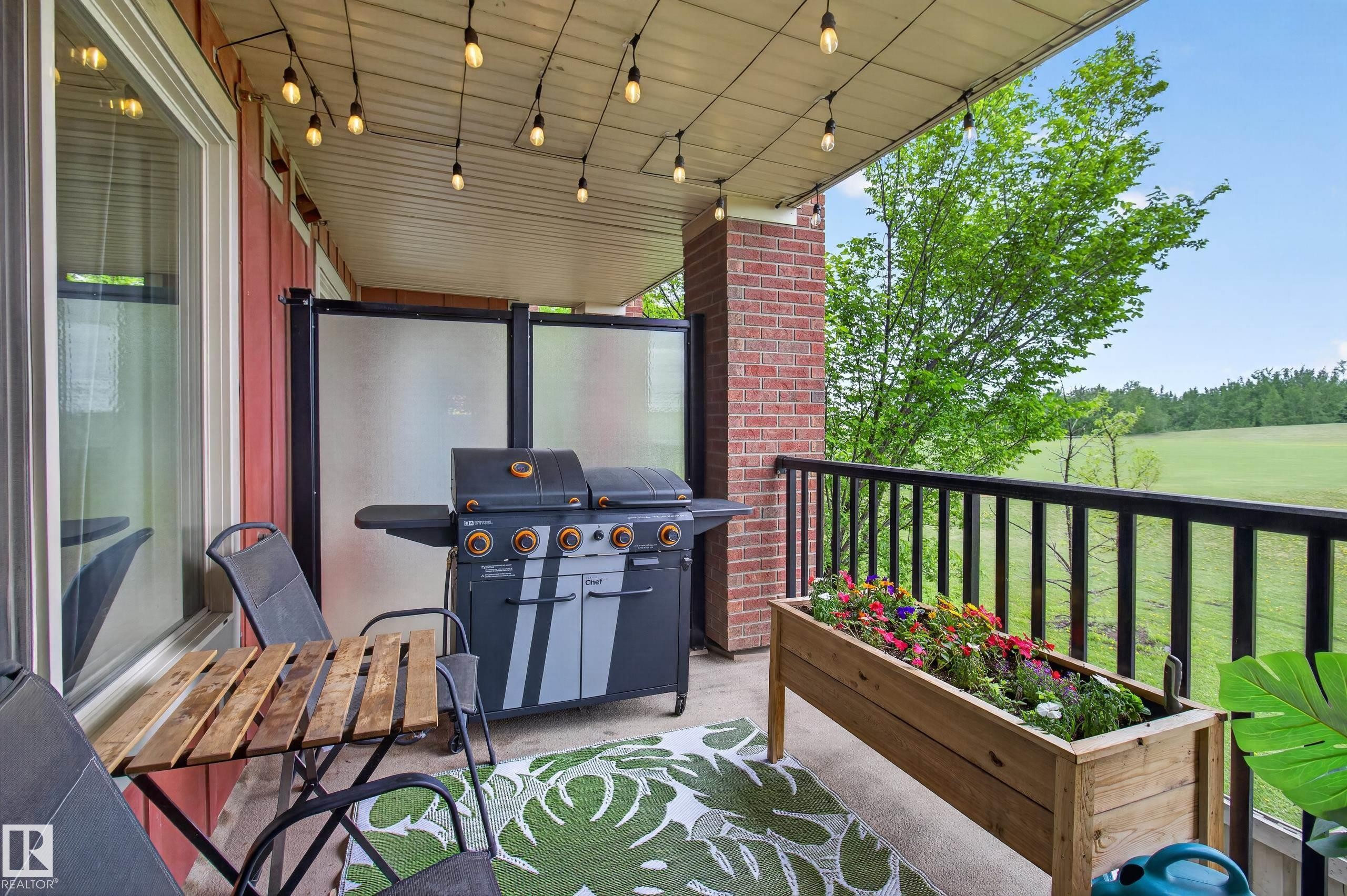 Covered outdoor patio featuring string lighting, brick accents, and privacy panels - 211 3719 Whitelaw Lane, Edmonton, AB