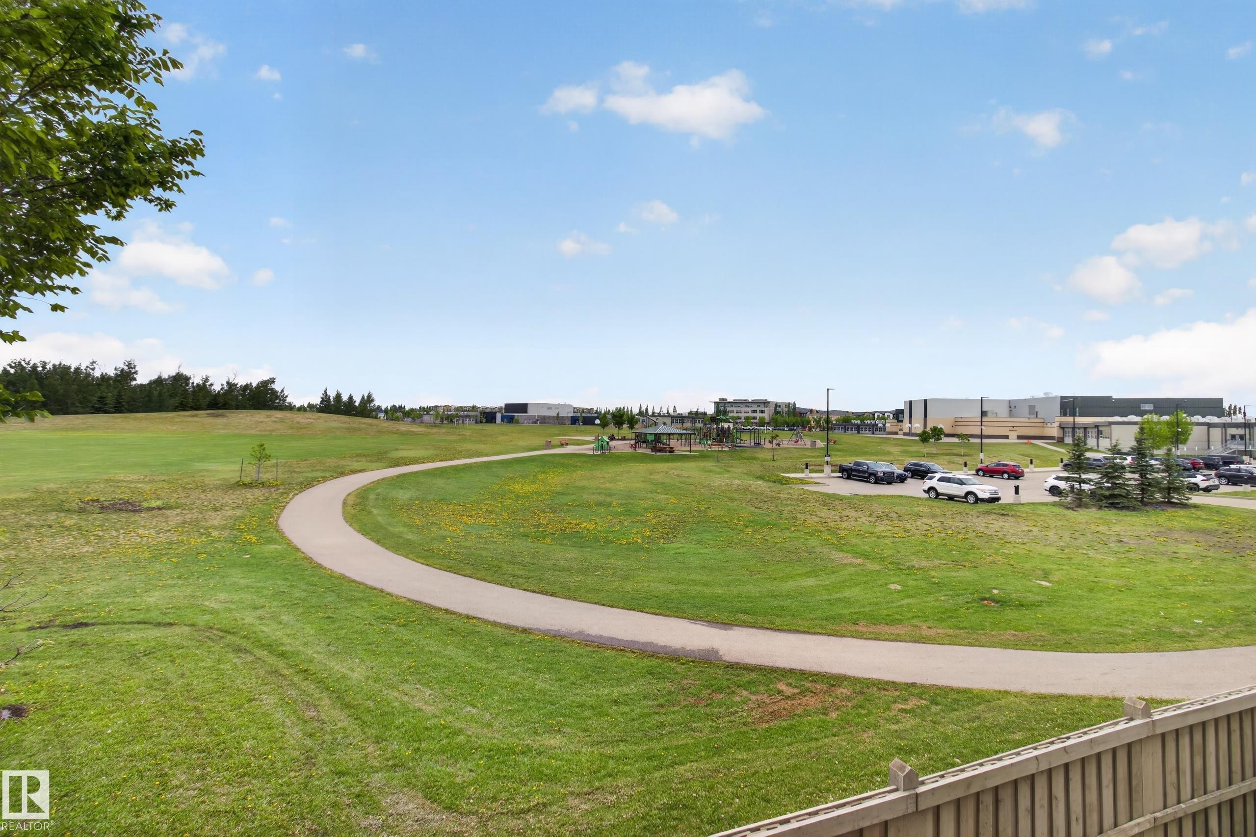 Expansive green space featuring a paved walking path, mature trees, and landscaping - 211 3719 Whitelaw Lane, Edmonton, AB