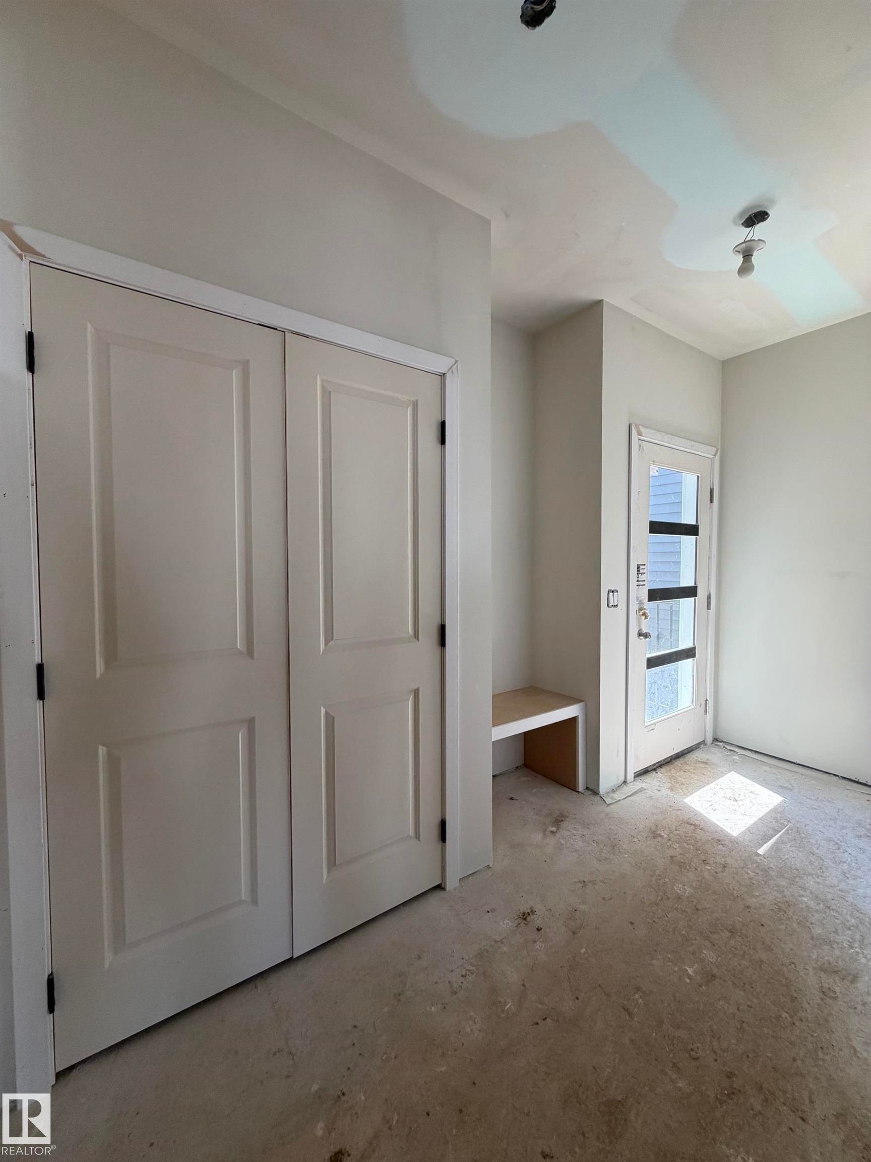 Entryway featuring double panel doors, built-in bench seating, and a glass-paneled entry door - 2206 Crossbill Link, Edmonton, AB