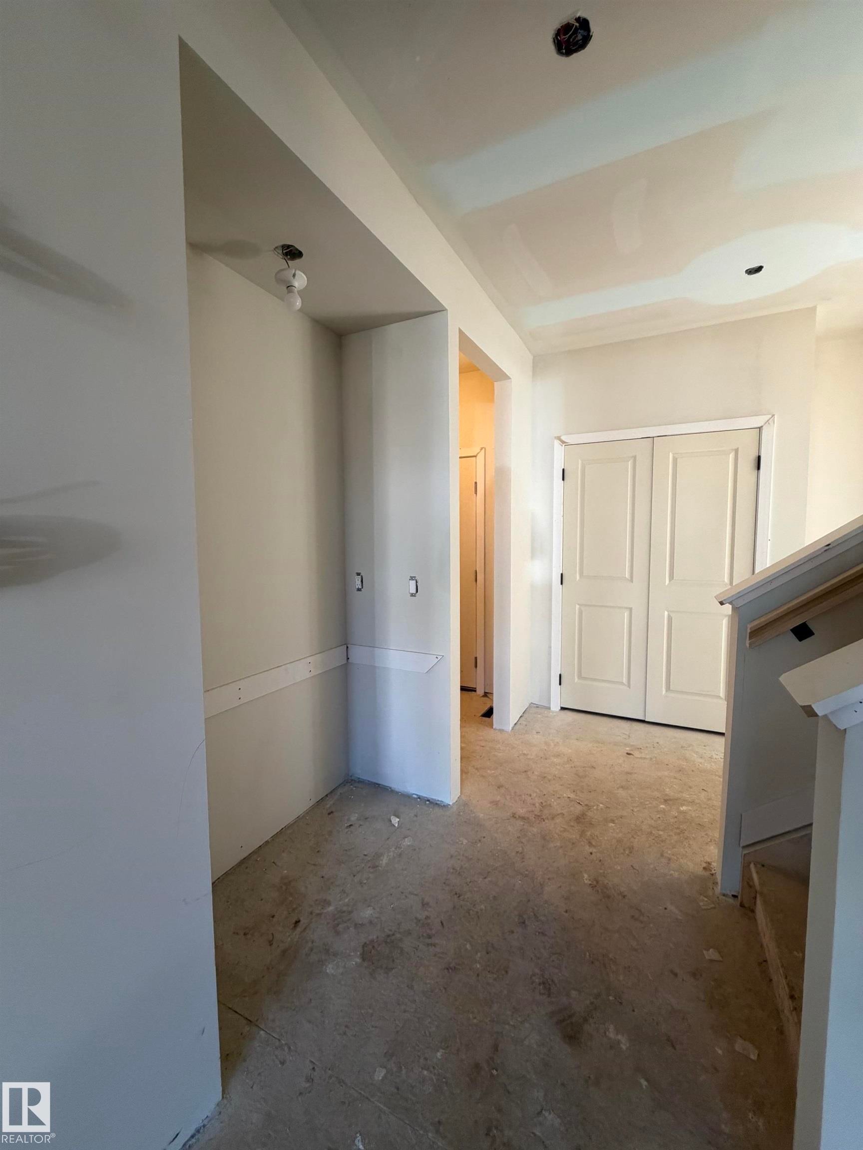Entryway featuring a built-in niche, unfinished flooring, and a pair of panel doors - 2206 Crossbill Link, Edmonton, AB