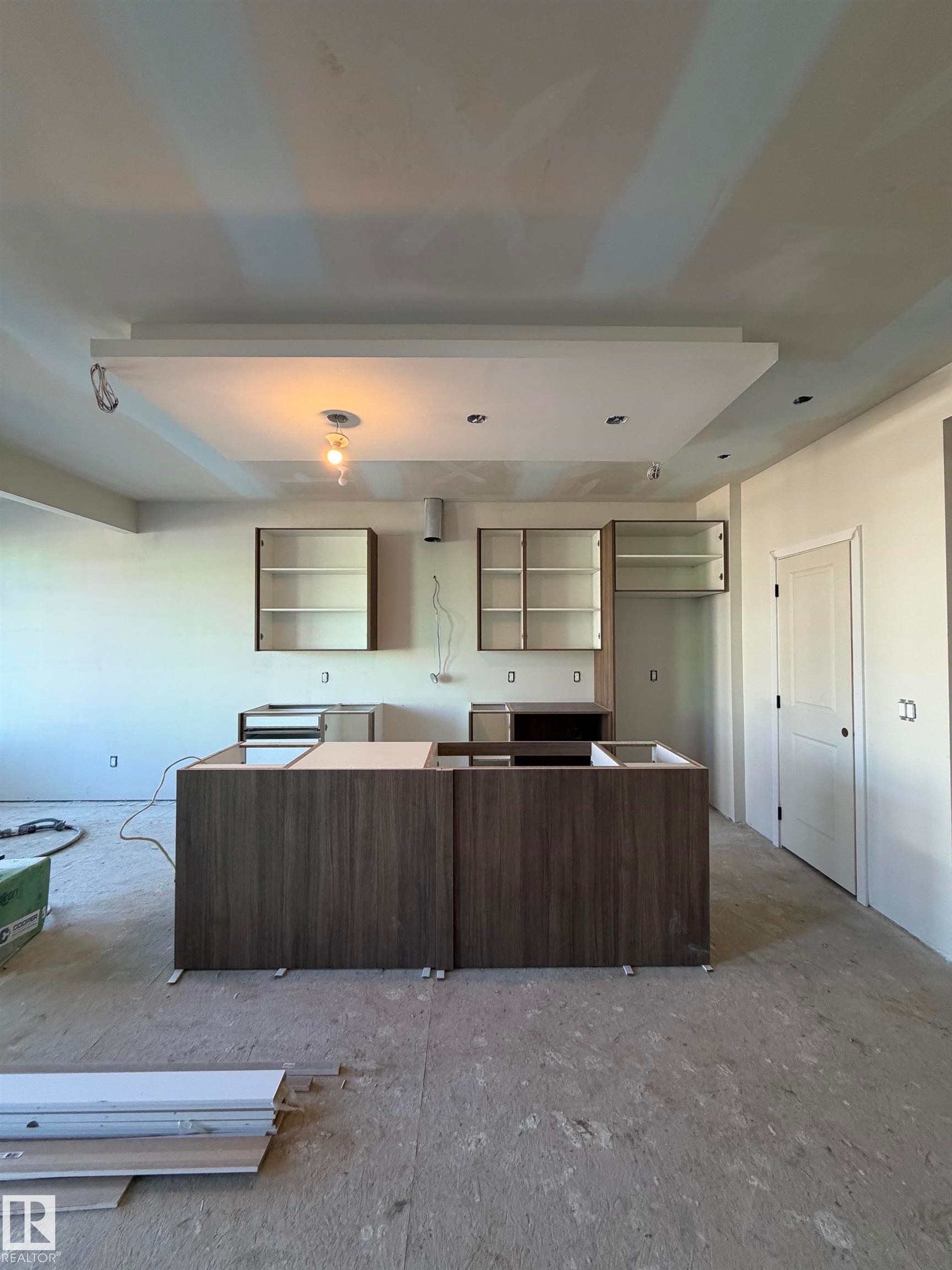 Kitchen space featuring a recessed ceiling, recessed lighting, and a partially installed island with wood-grain base cabinetry - 2206 Crossbill Link, Edmonton, AB