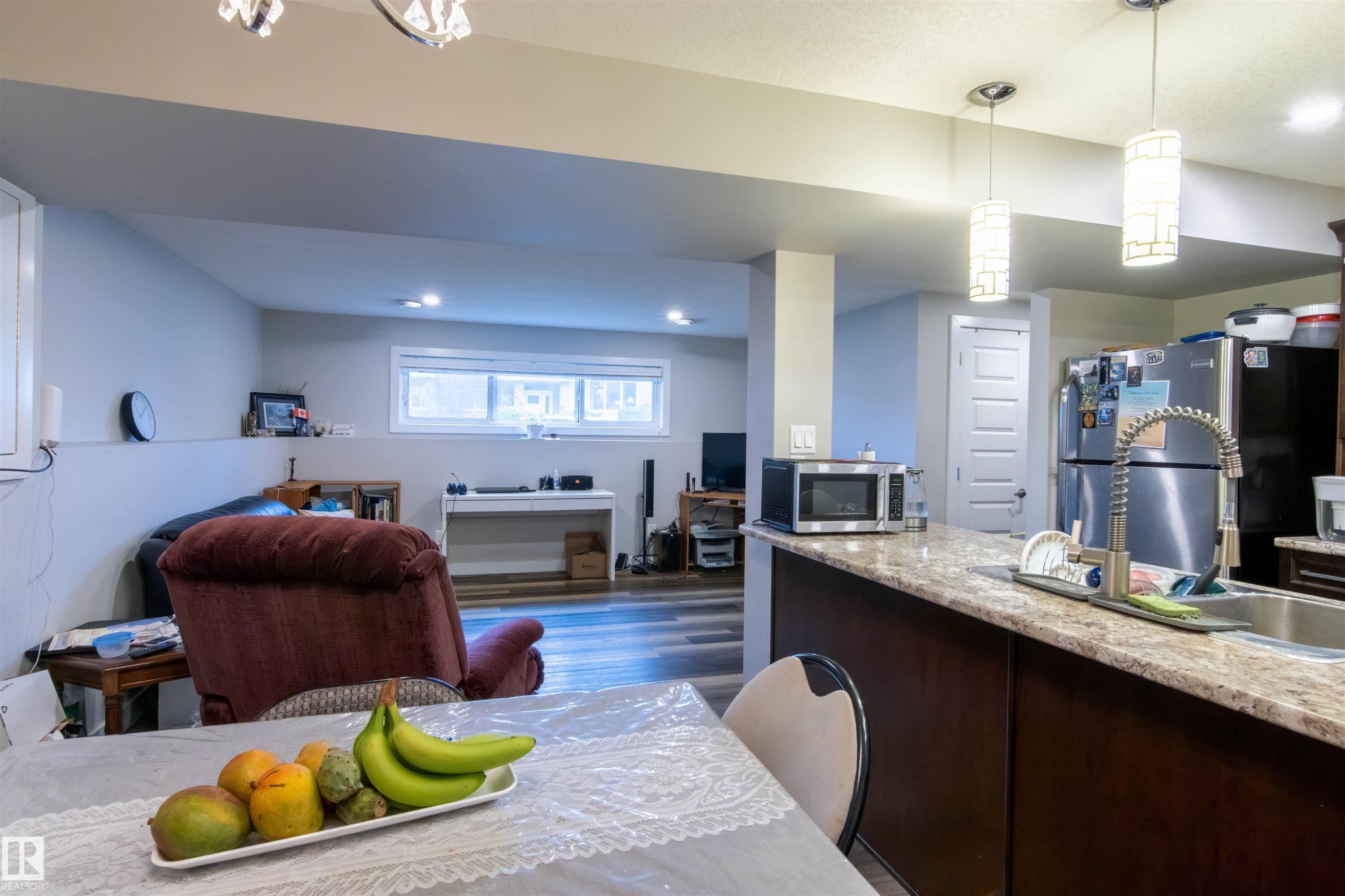 Kitchen island with a light-toned countertop and dark wood-finish cabinetry - 4004 88 Street Nw, Edmonton, AB - Indoor