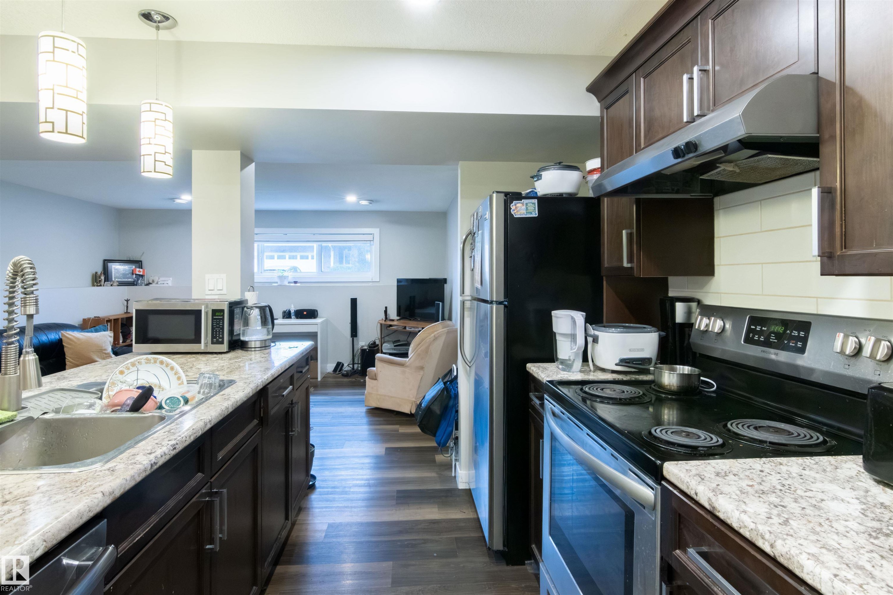 Kitchen featuring dark wood cabinetry, granite-style countertops, stainless steel appliances, and wood-finish flooring - 4004 88 Street Nw, Edmonton, AB - Indoor Photo Showing Kitchen