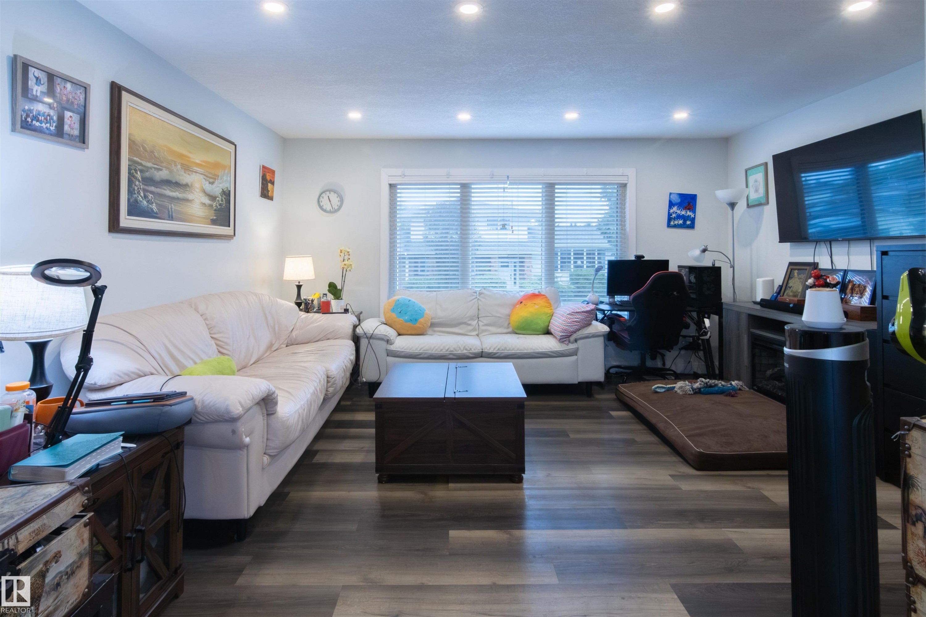 Spacious living area featuring wood-finish flooring, recessed lighting, and a prominent window - 4004 88 Street Nw, Edmonton, AB - Indoor Photo Showing Living Room