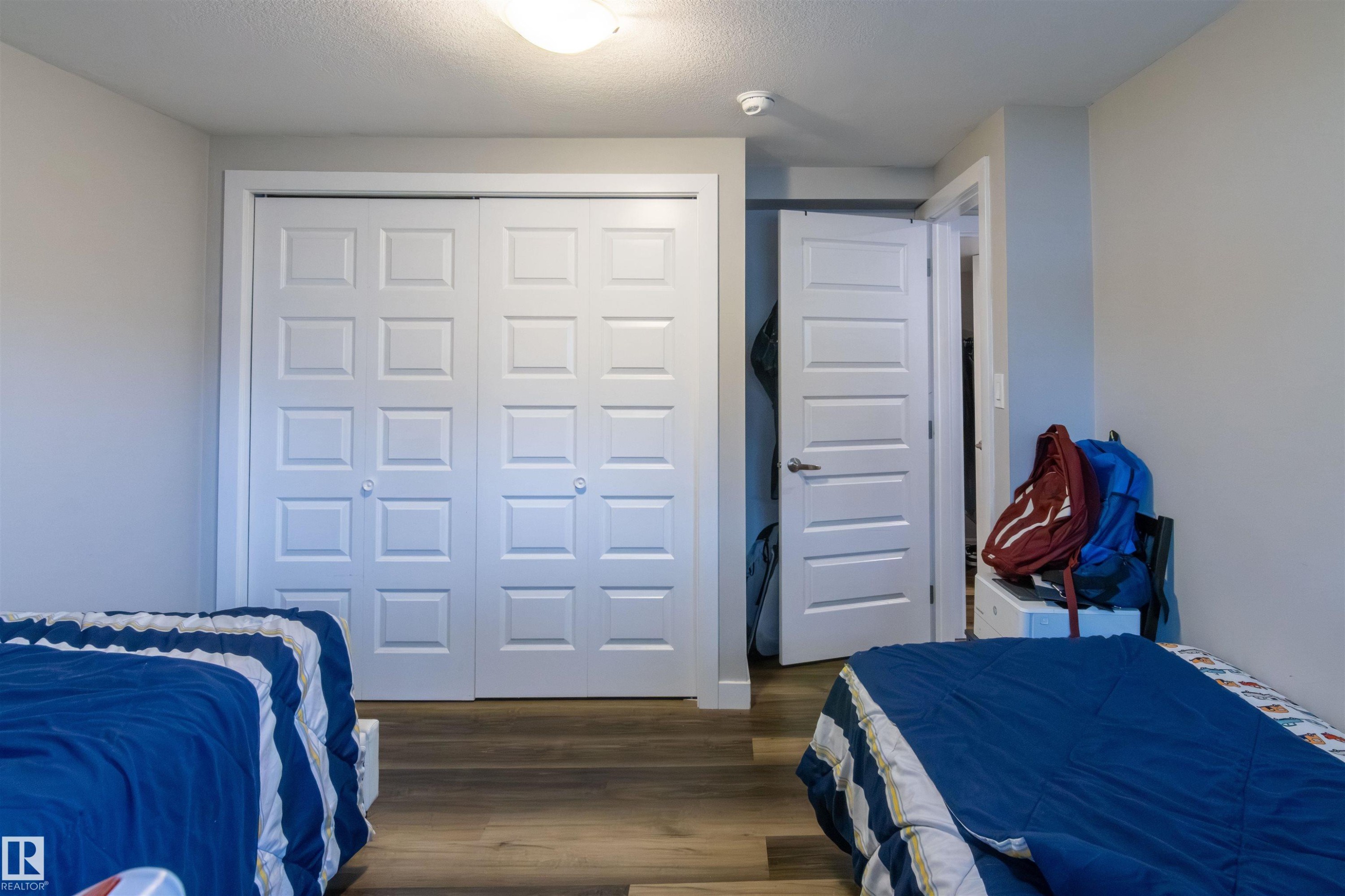 White sliding panel closet doors with brass-tone knobs - 4004 88 Street Nw, Edmonton, AB - Indoor Photo Showing Bedroom