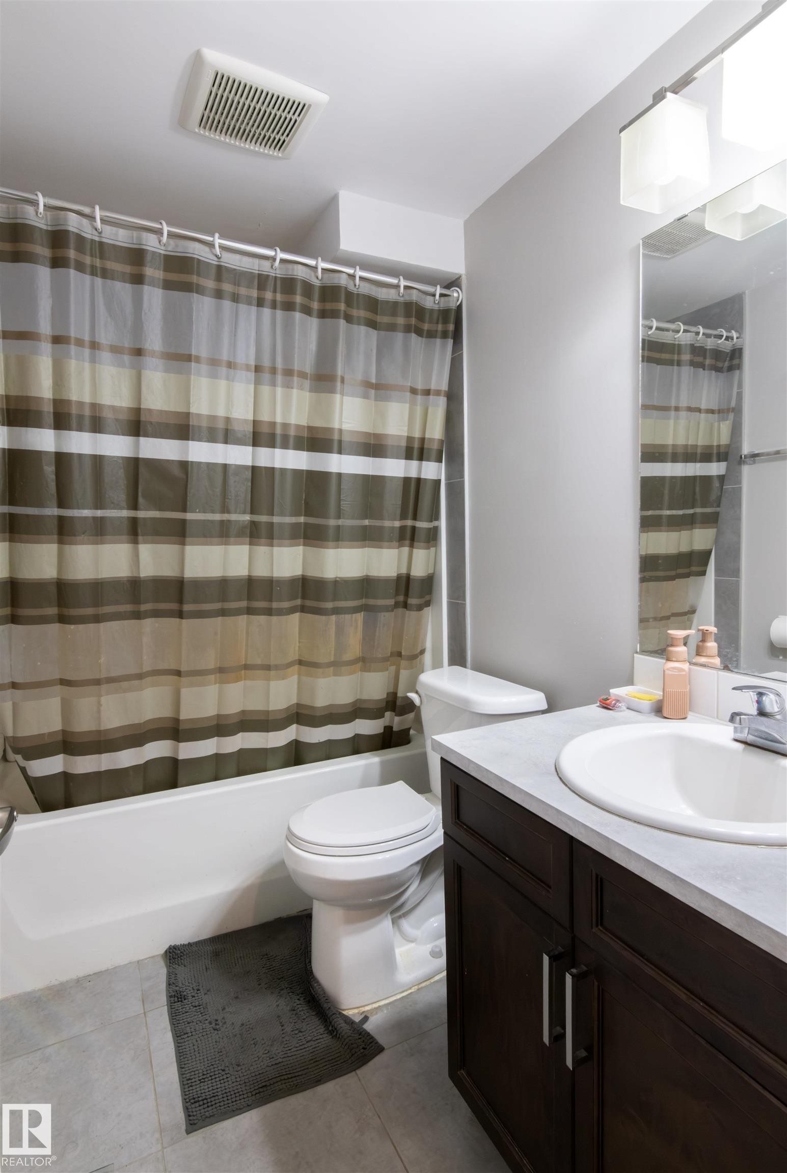 Bathroom featuring a dark wood-finish vanity with a light countertop, an undermount sink, and a mirrored wall - 4004 88 Street Nw, Edmonton, AB - Indoor Photo Showing Bathroom