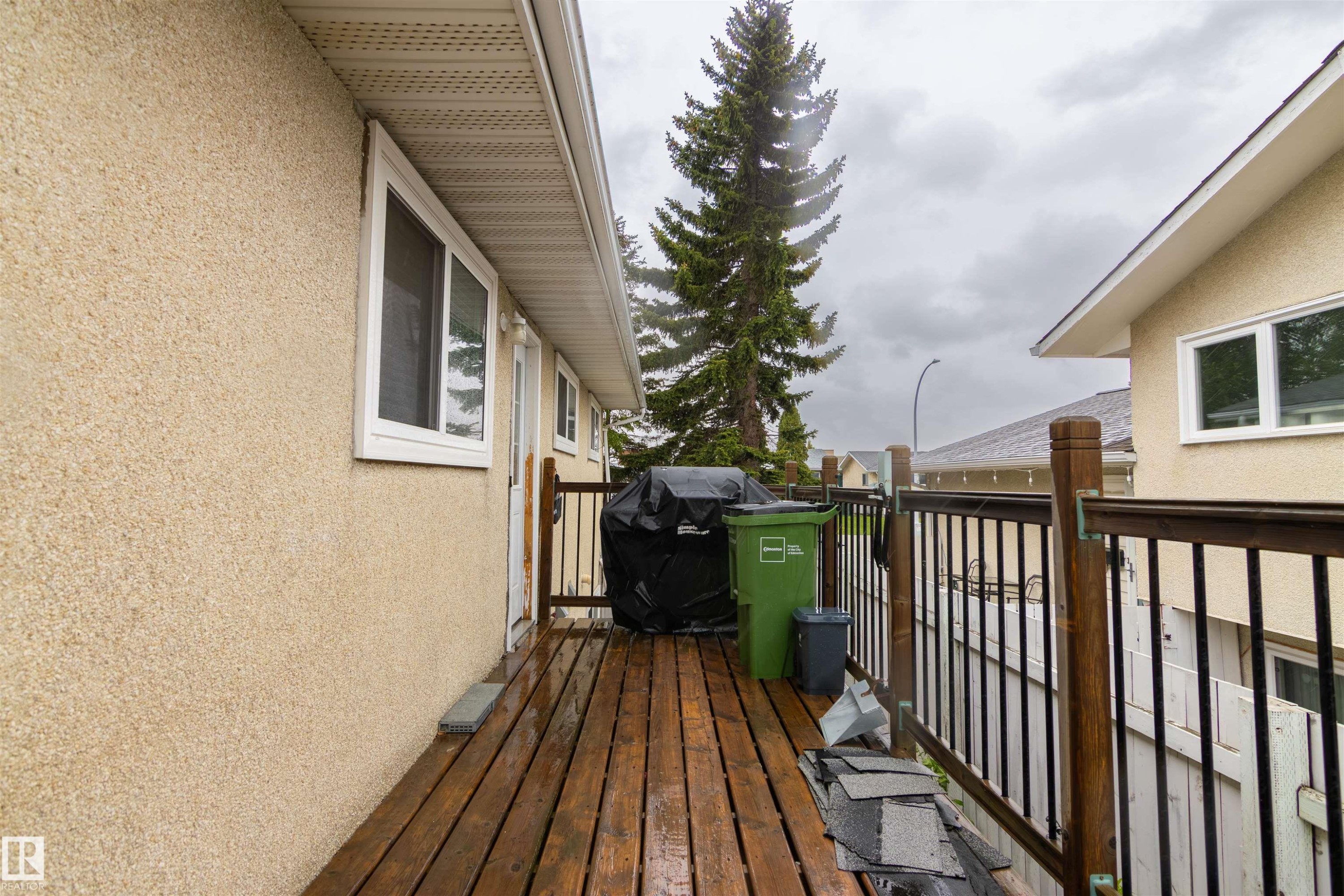 Wood-finish deck with dark-stained railings and black metal balusters - 4004 88 Street Nw, Edmonton, AB - Outdoor With Exterior