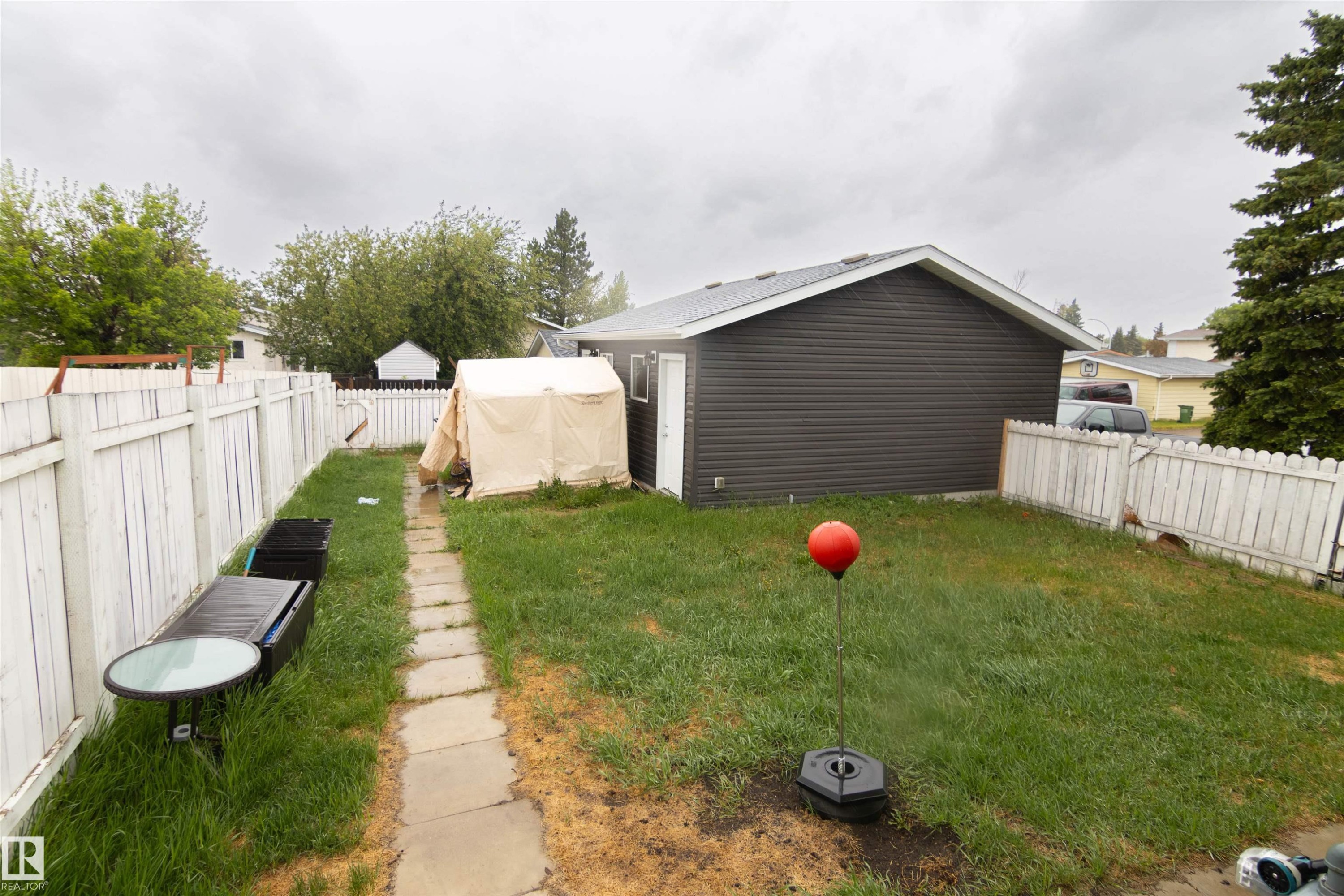 Expansive backyard featuring a stone pathway, white picket fencing, and a detached building with dark horizontal siding - 4004 88 Street Nw, Edmonton, AB - Outdoor
