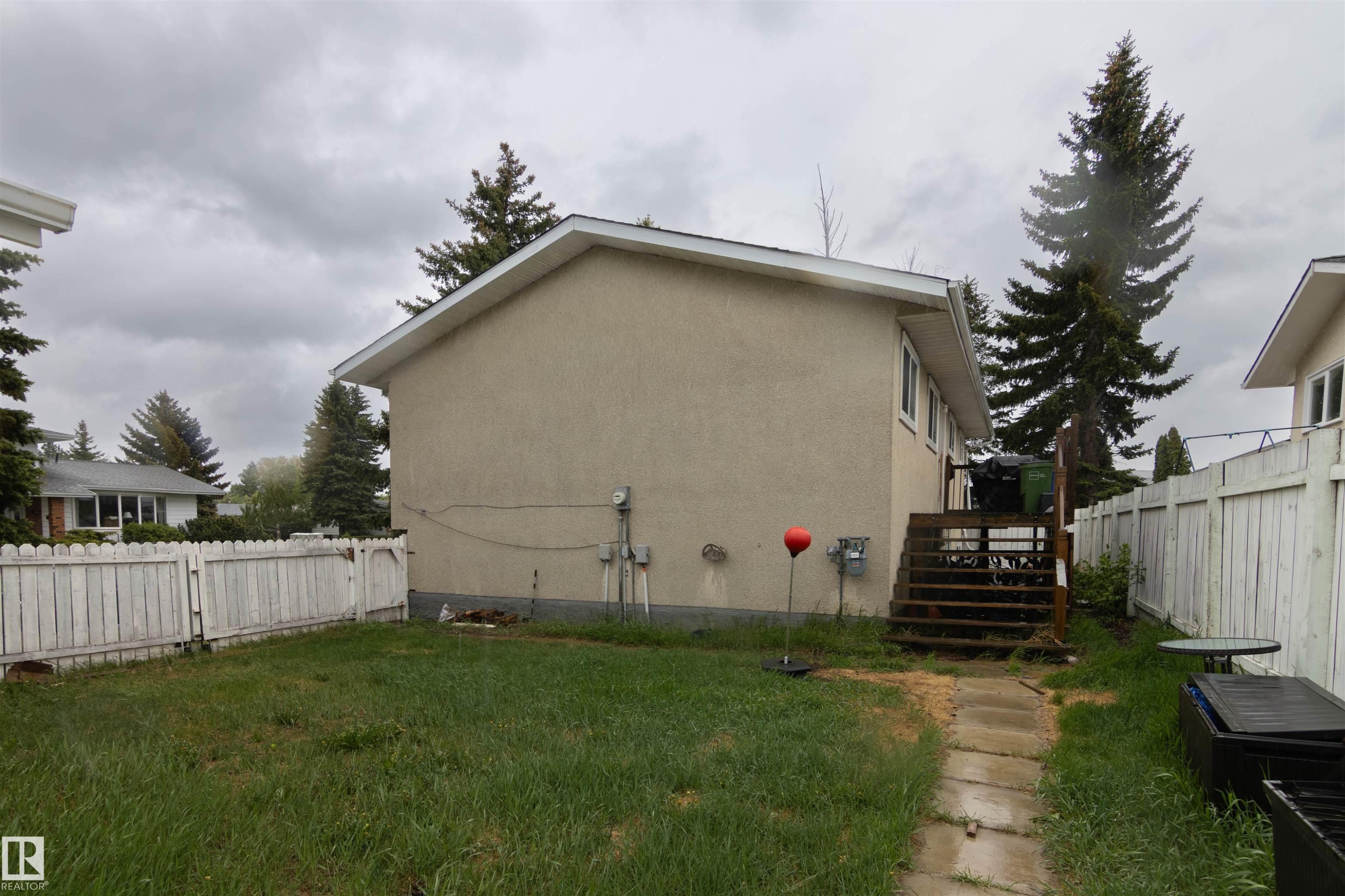 Rear exterior featuring stucco siding, white trim, and a wood deck - 4004 88 Street Nw, Edmonton, AB - Outdoor