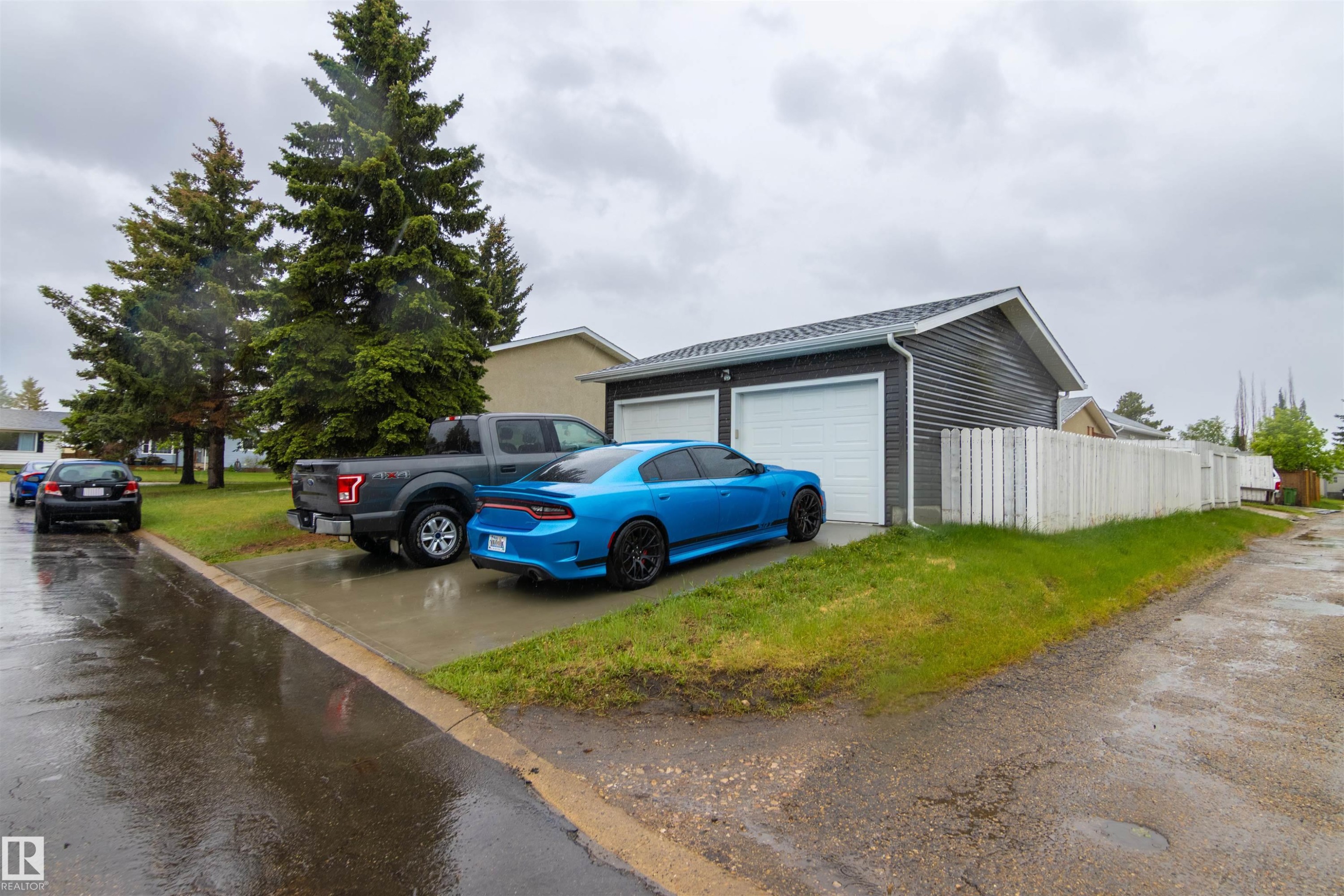 Detached garage with two white overhead doors and dark gray horizontal siding - 4004 88 Street Nw, Edmonton, AB - Outdoor