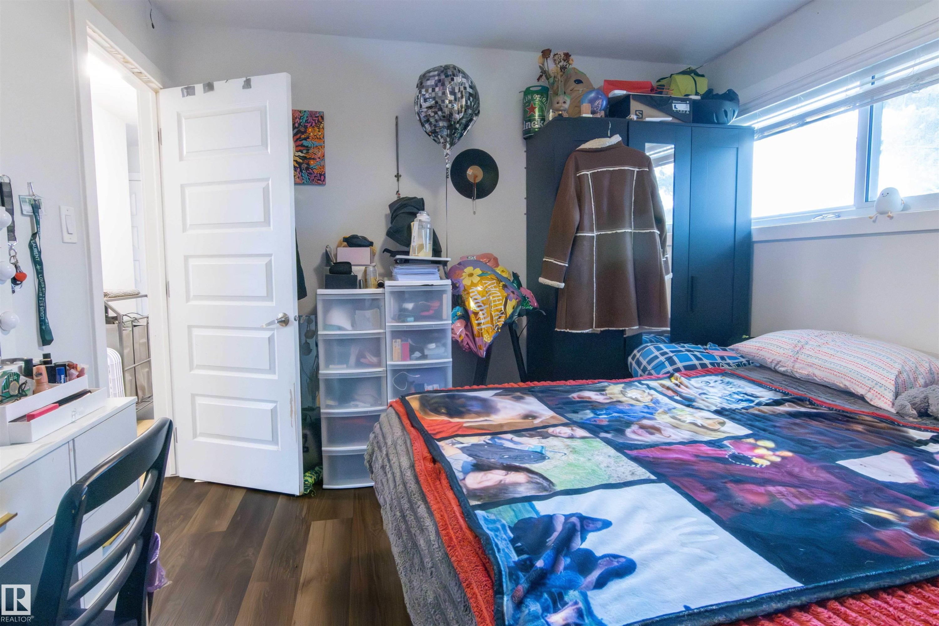 Room featuring wood-finish flooring, a white five-panel interior door, and a horizontal window - 4004 88 Street Nw, Edmonton, AB - Indoor Photo Showing Bedroom