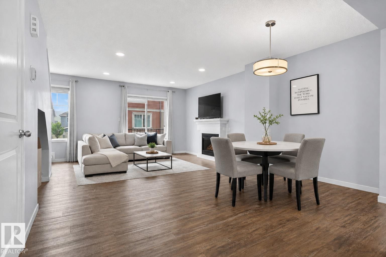 Open-concept living space featuring wood-finish flooring, recessed lighting, and a white fireplace - 62 3305 Orchards Link, Edmonton, AB