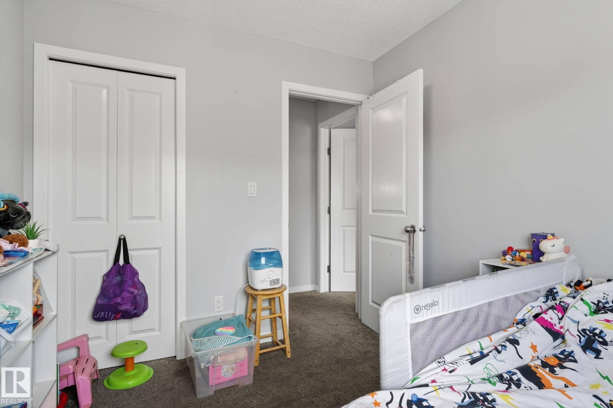 Interior room featuring neutral wall paint, white trim, and dark carpet flooring - 62 3305 Orchards Link, Edmonton, AB