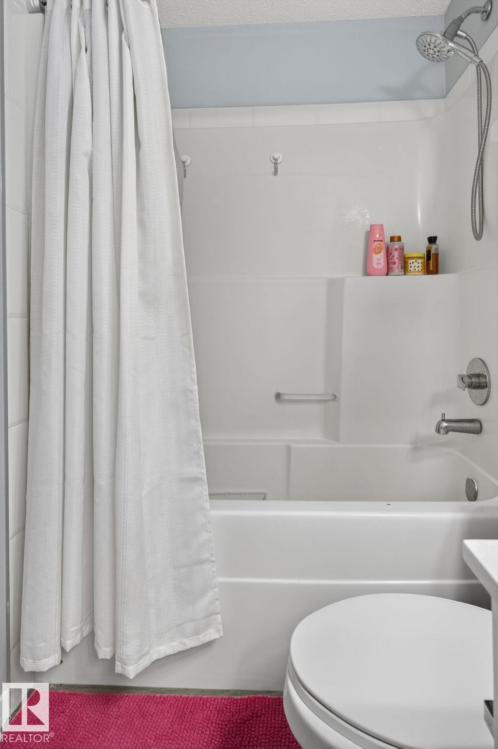 White acrylic bathtub and shower combination with an integrated soap shelf and a chrome shower head with handheld sprayer - 62 3305 Orchards Link, Edmonton, AB