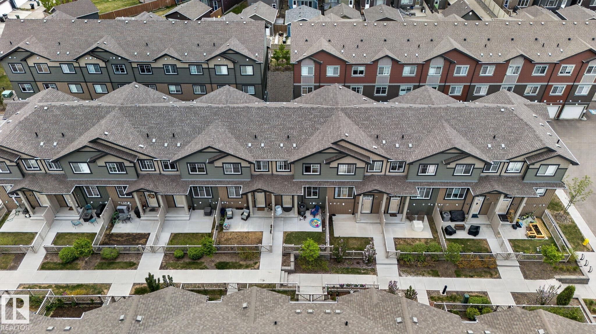 Aerial perspective highlighting a row of modern townhomes with private fenced yards - 62 3305 Orchards Link, Edmonton, AB