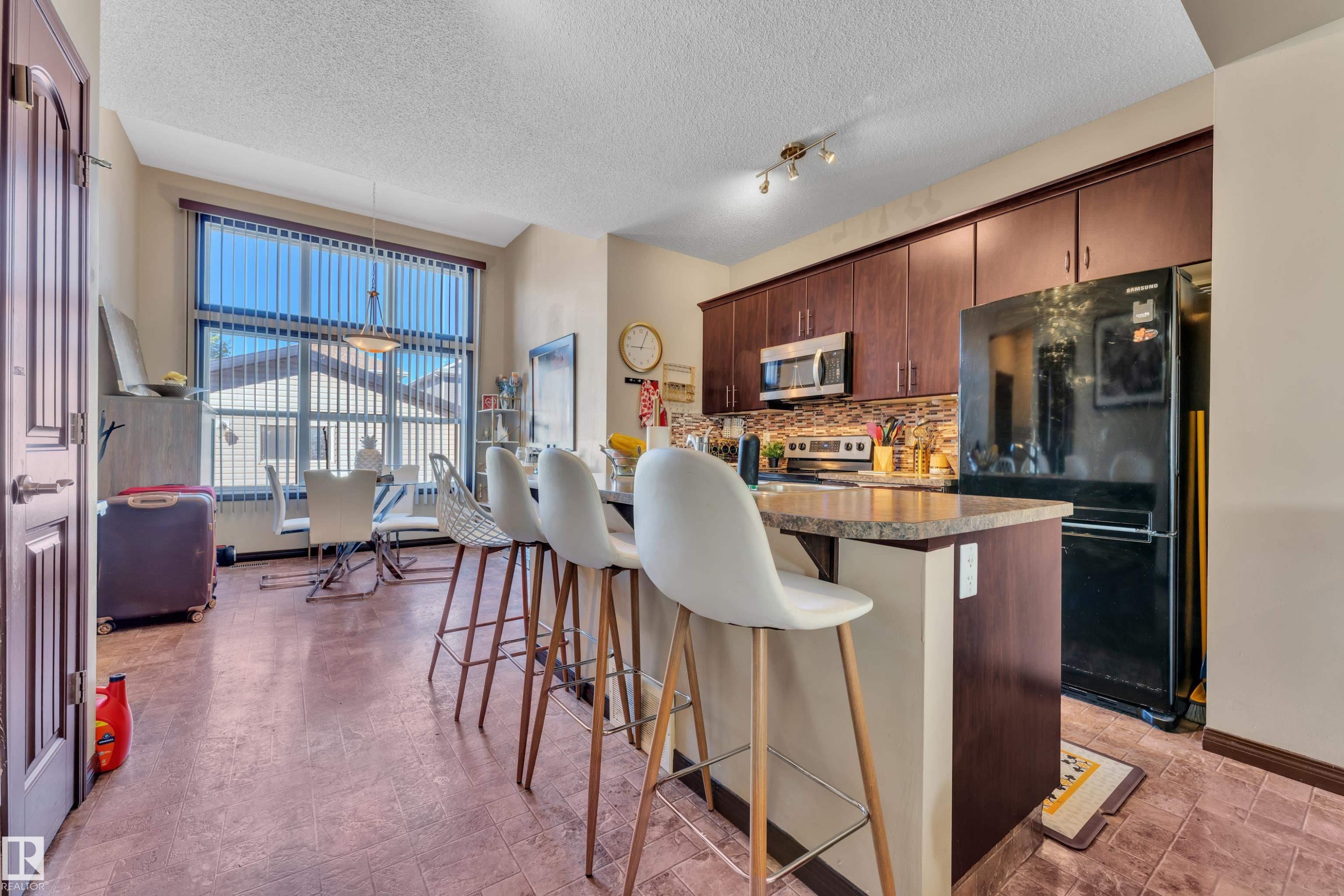 Functional kitchen featuring dark wood cabinetry, stainless steel appliances, and a tiled backsplash - 621 Mcdonough Link Link, Edmonton, AB
