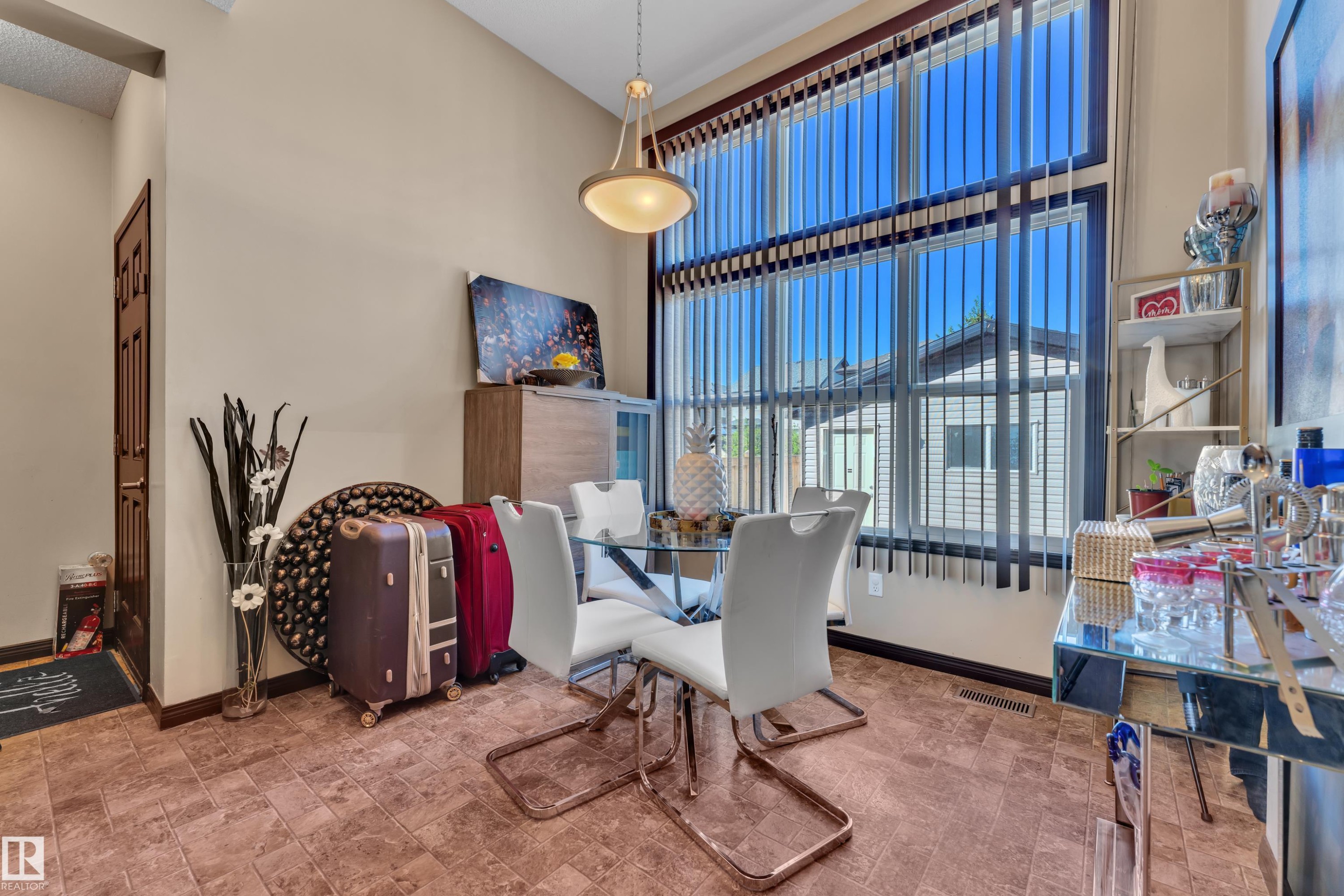 Dining area featuring a soaring ceiling, a full-height window with vertical blinds, and tile flooring - 621 Mcdonough Link Link, Edmonton, AB