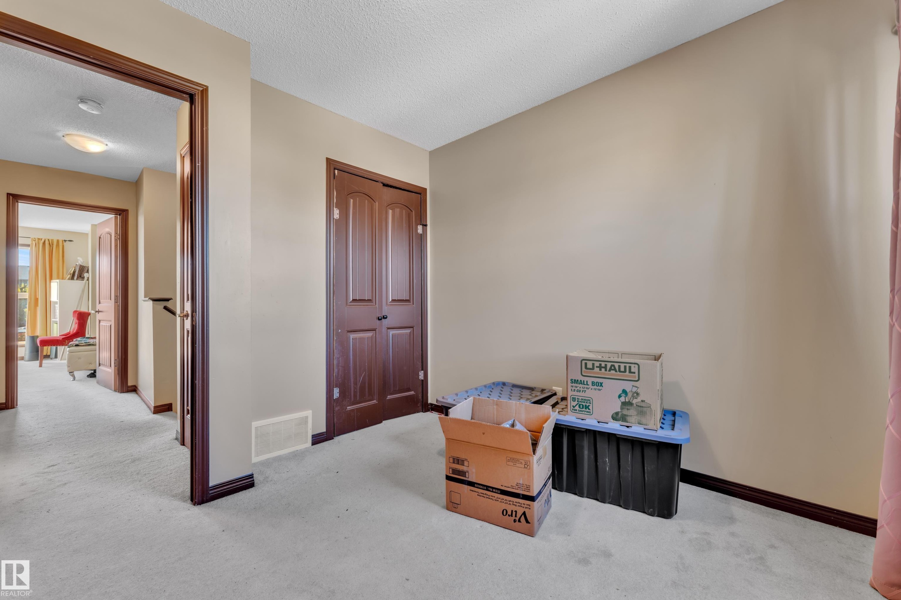 Carpeted room featuring a double-door closet, neutral wall paint, and dark wood trim - 621 Mcdonough Link Link, Edmonton, AB