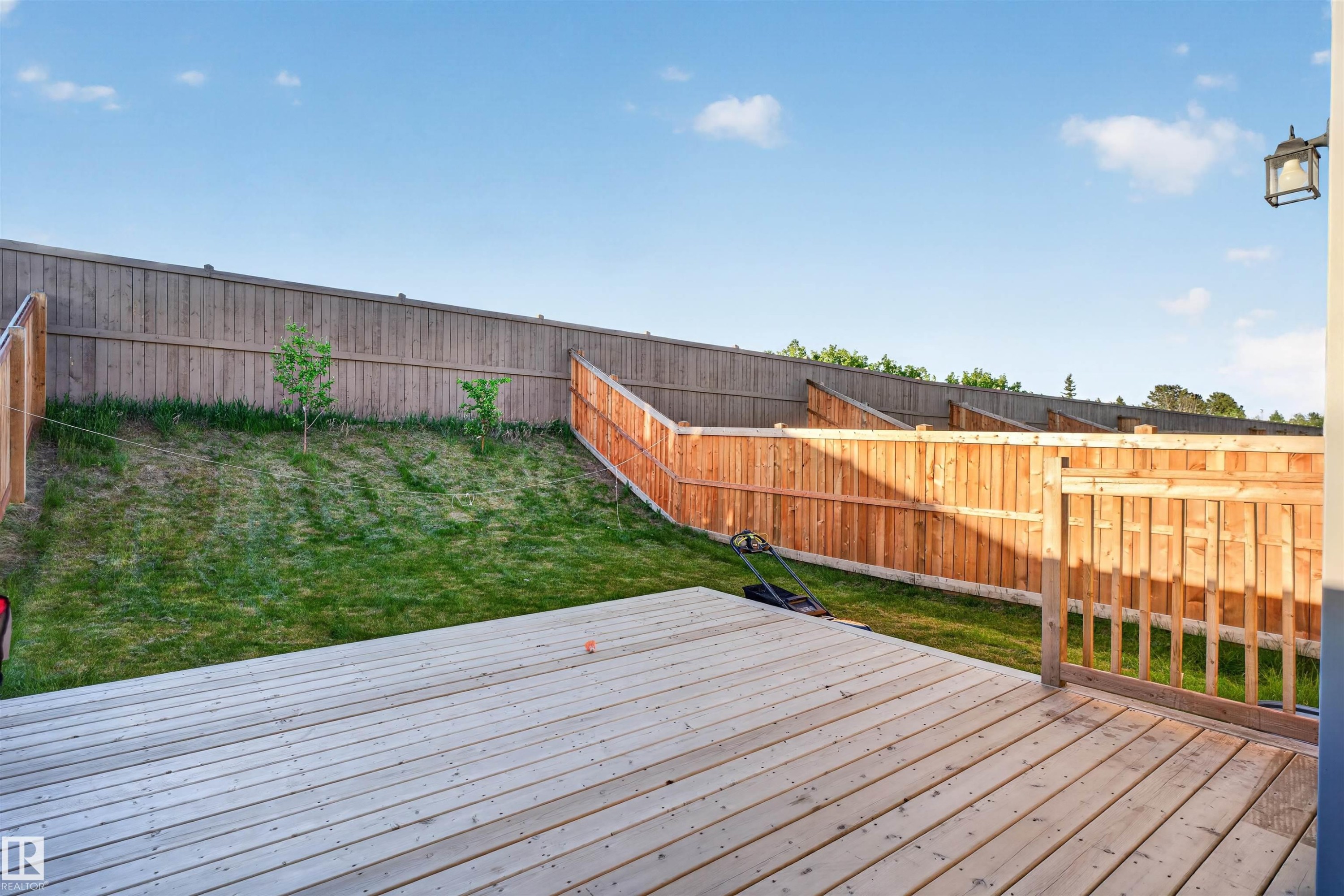 Expansive wood deck with a full wood railing, overlooking a sloped grass yard - 22638 99A Avenue, Edmonton, AB
