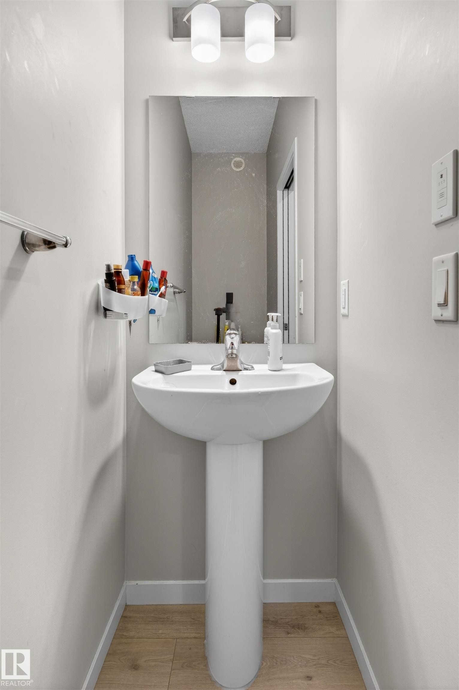 Pedestal sink with a polished chrome faucet, rectangular wall mirror, and brushed nickel two-light vanity fixture - 22638 99A Avenue, Edmonton, AB
