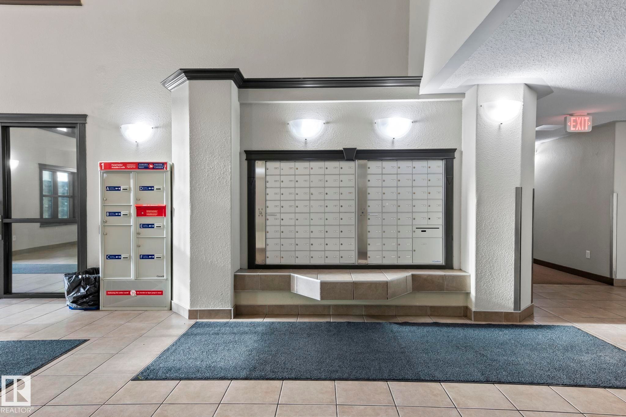 Interior common area featuring tile flooring, built-in mailboxes, and wall sconce lighting - 2106 9357 Simpson Dr Nw, Edmonton, AB - Indoor Photo Showing Other Room