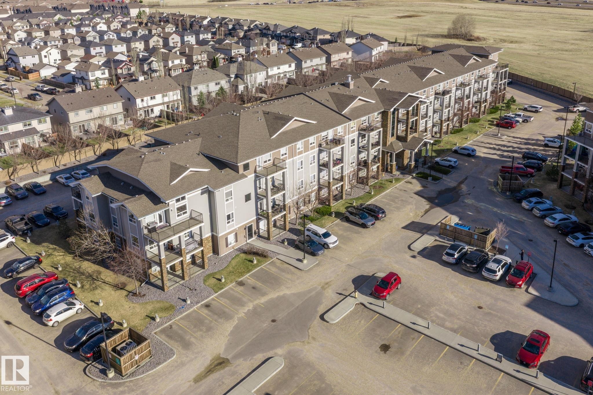 Multi-story residential building featuring light grey siding and dark brown stone accents - 2106 9357 Simpson Dr Nw, Edmonton, AB - With View