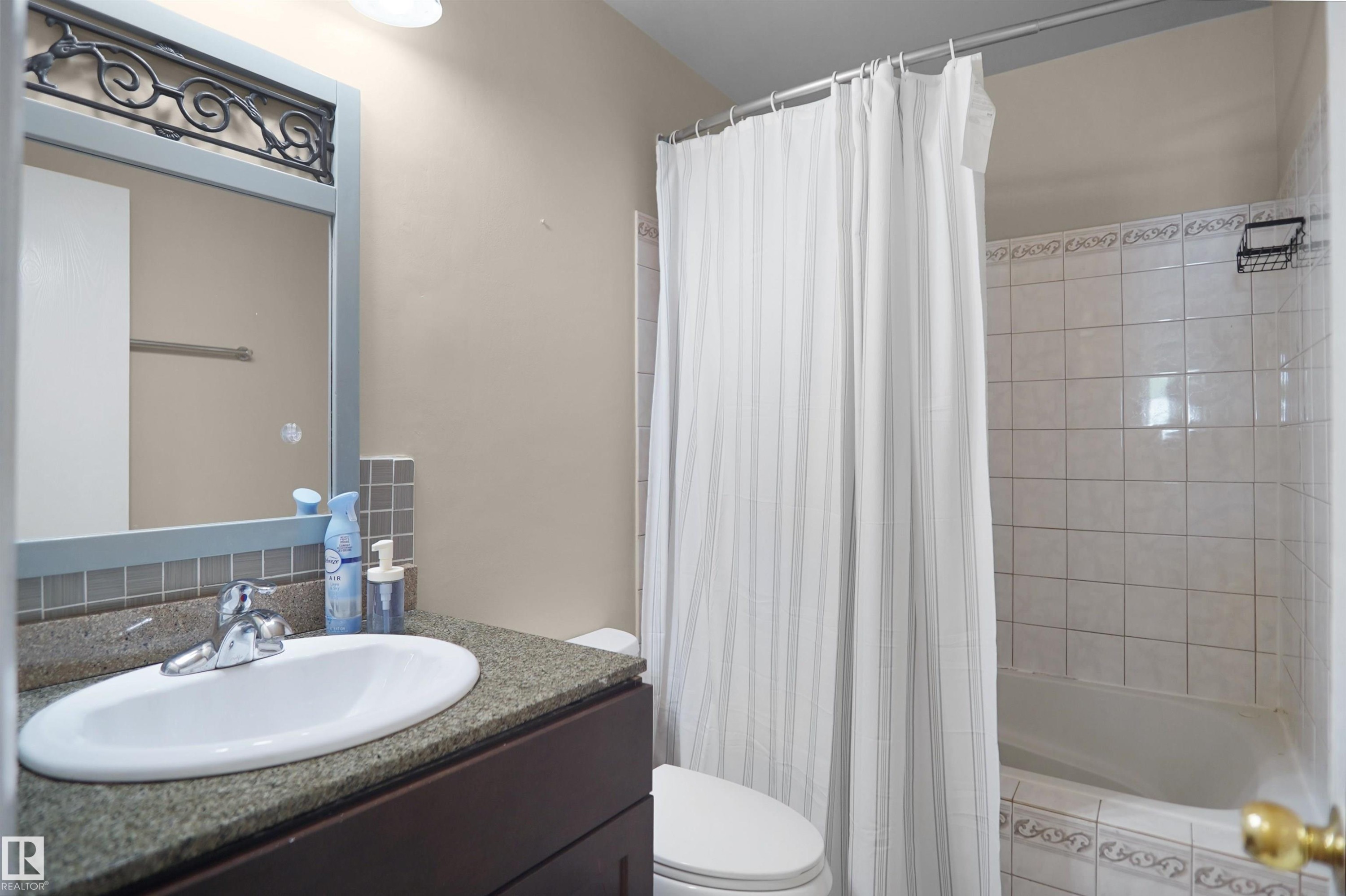 Bathroom featuring a vanity with an undermount sink, a dark wood-finish cabinet, and a speckled countertop - 13524 26 Street, Edmonton, AB