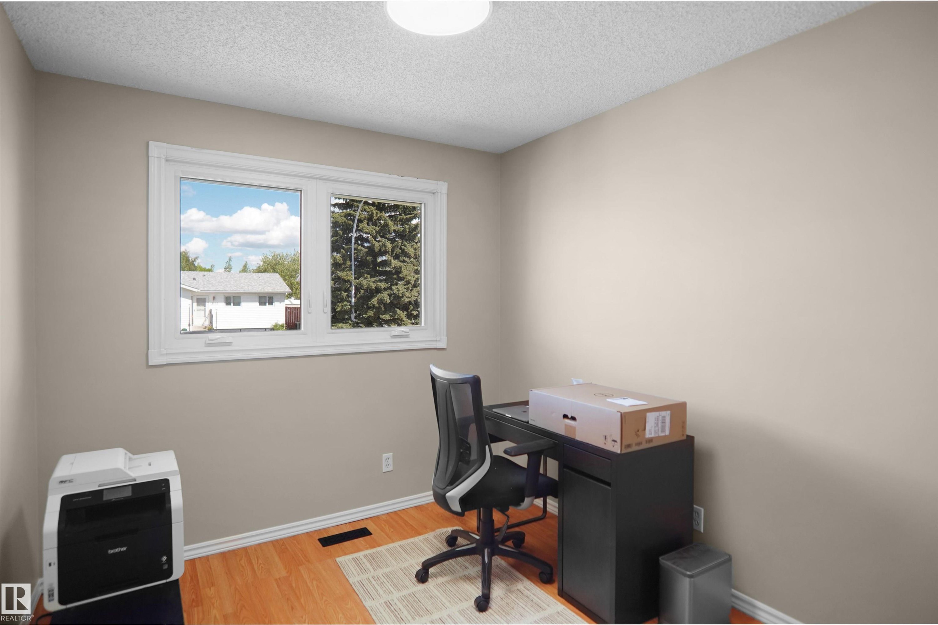 Neutral-toned interior room with wood-finish flooring, a white window frame, and a white ceiling - 13524 26 Street, Edmonton, AB