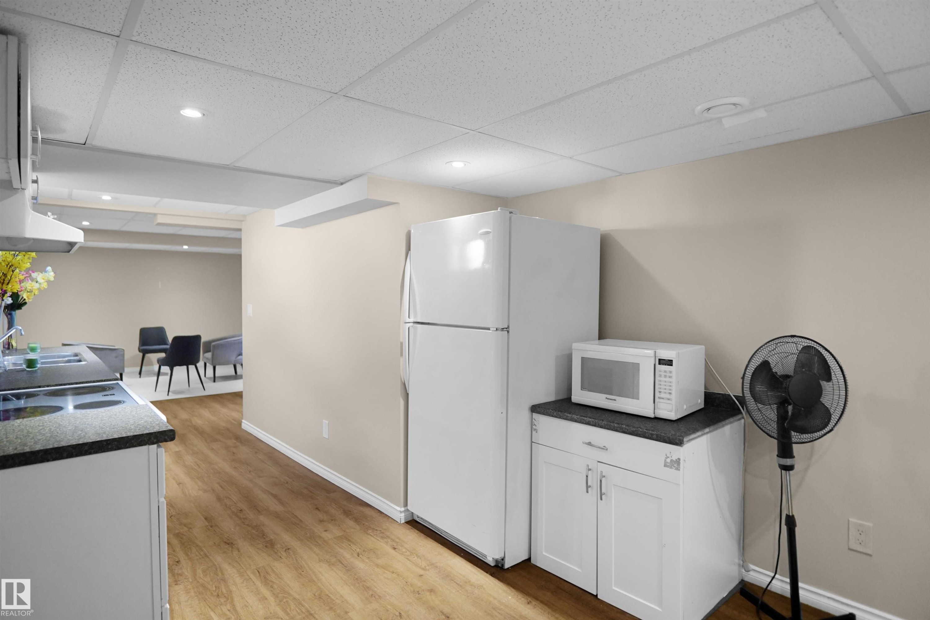 Kitchenette featuring wood-finish flooring, white cabinetry, and a dark countertop - 13524 26 Street, Edmonton, AB