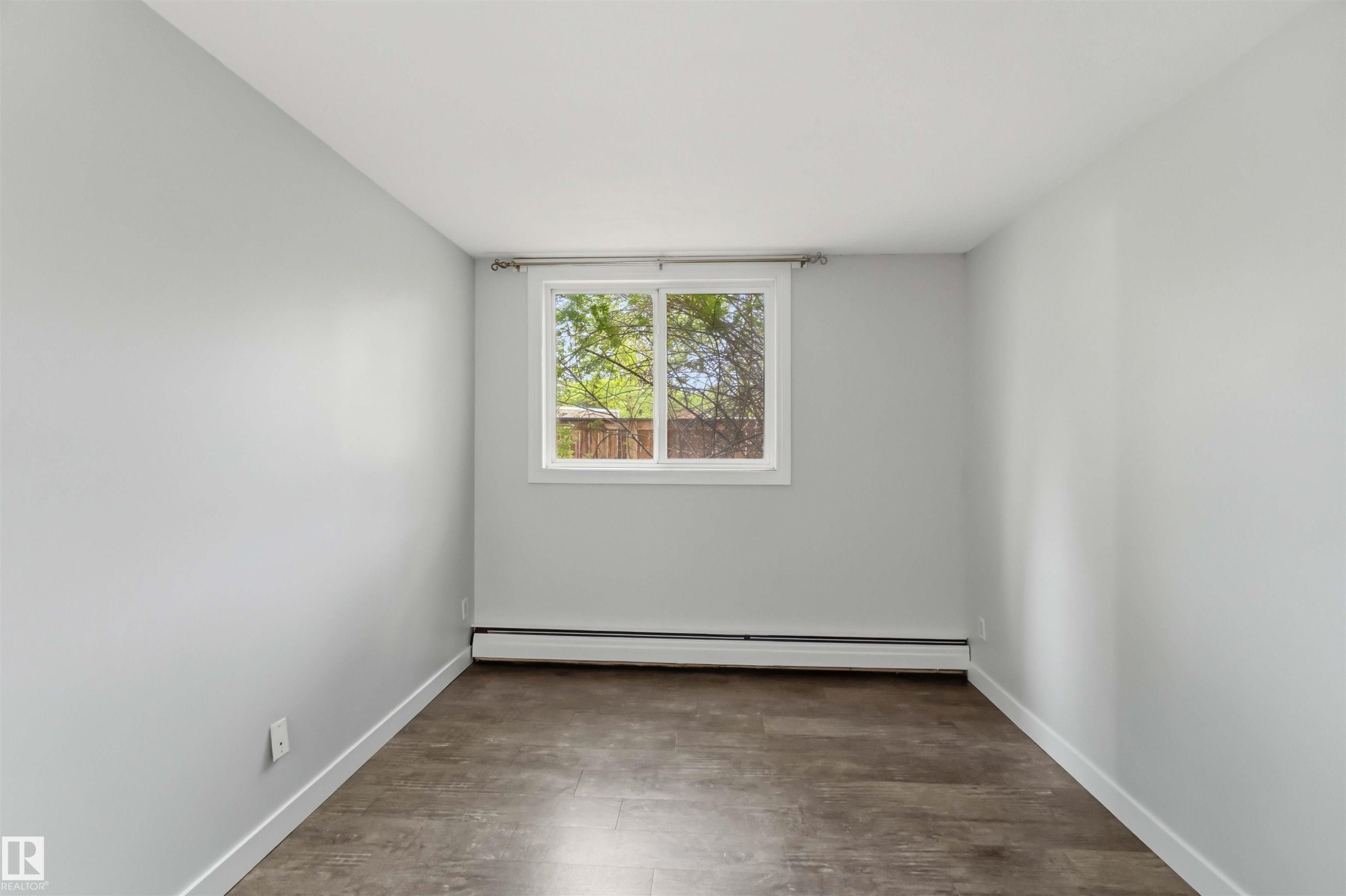 Room featuring light gray walls, wood-finish flooring, and a white-framed window - #121 5125 Riverbend Rd Nw Nw, Edmonton, AB - Indoor Photo Showing Other Room