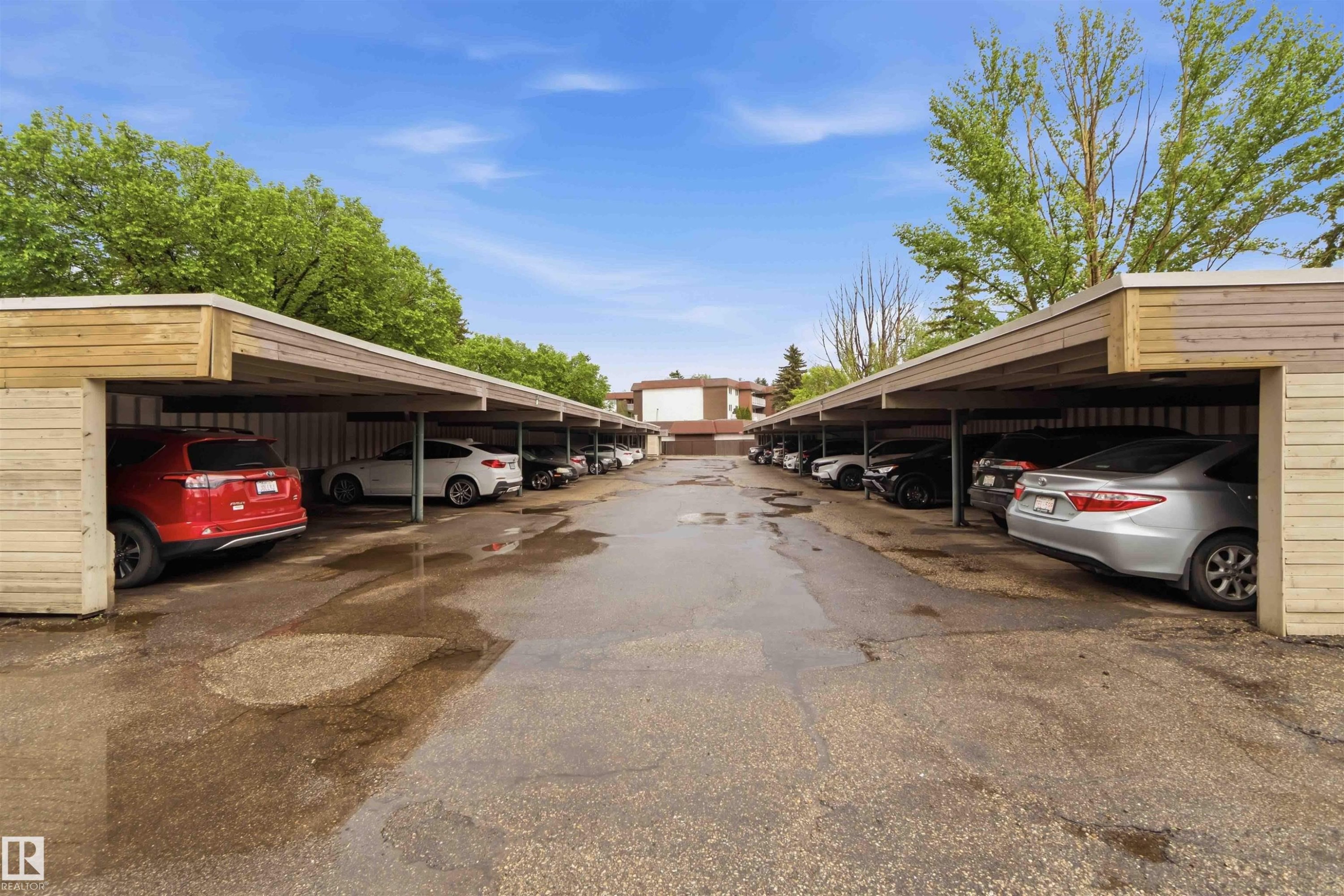 Covered parking area featuring multiple carport structures with wood-finish siding and flat roofs - #121 5125 Riverbend Rd Nw Nw, Edmonton, AB - Outdoor