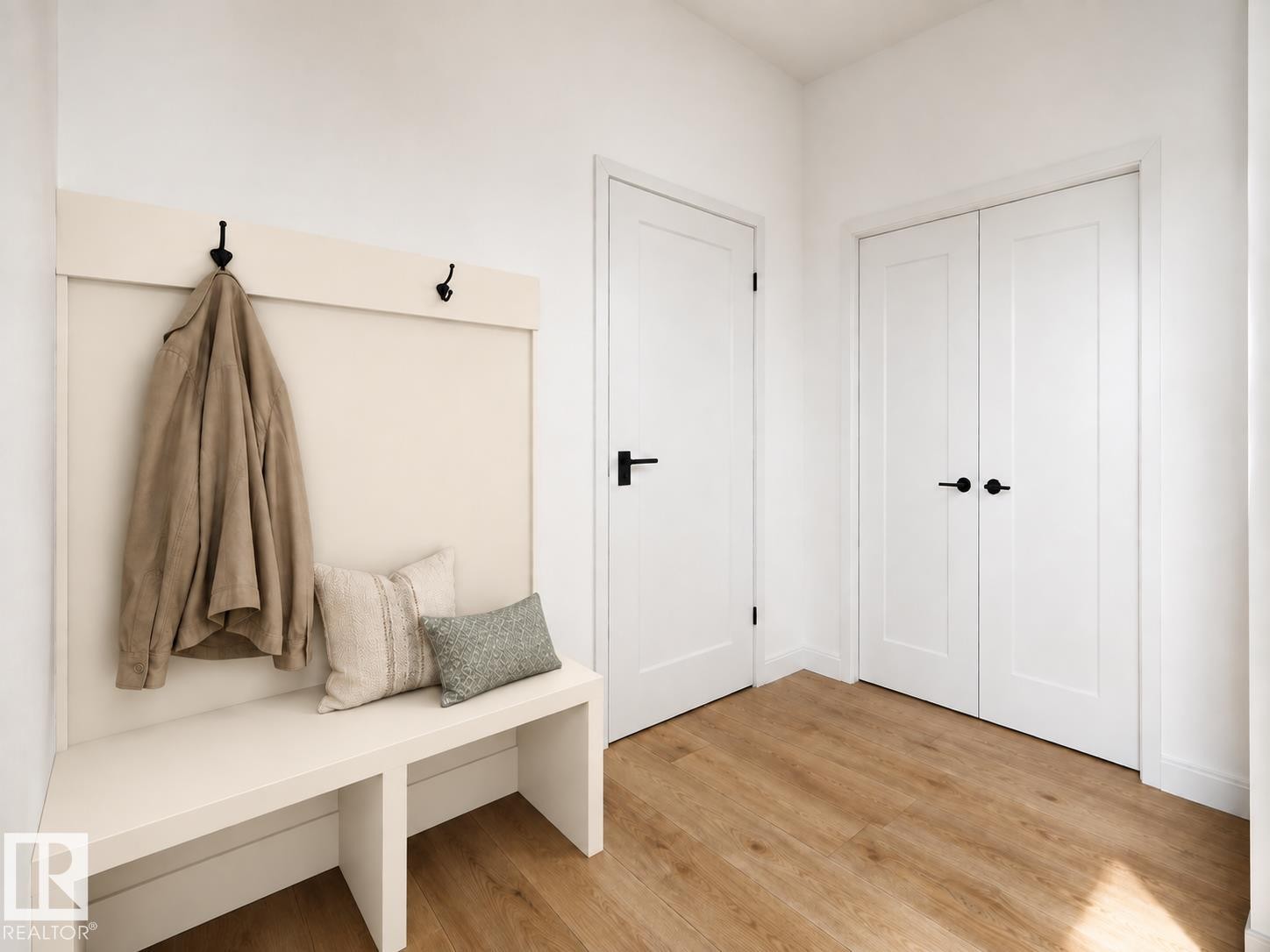 Built-in bench with integrated coat hooks, wood-finish flooring, and white paneled doors with matte black hardware - 11 Brickyard View, Stony Plain, AB