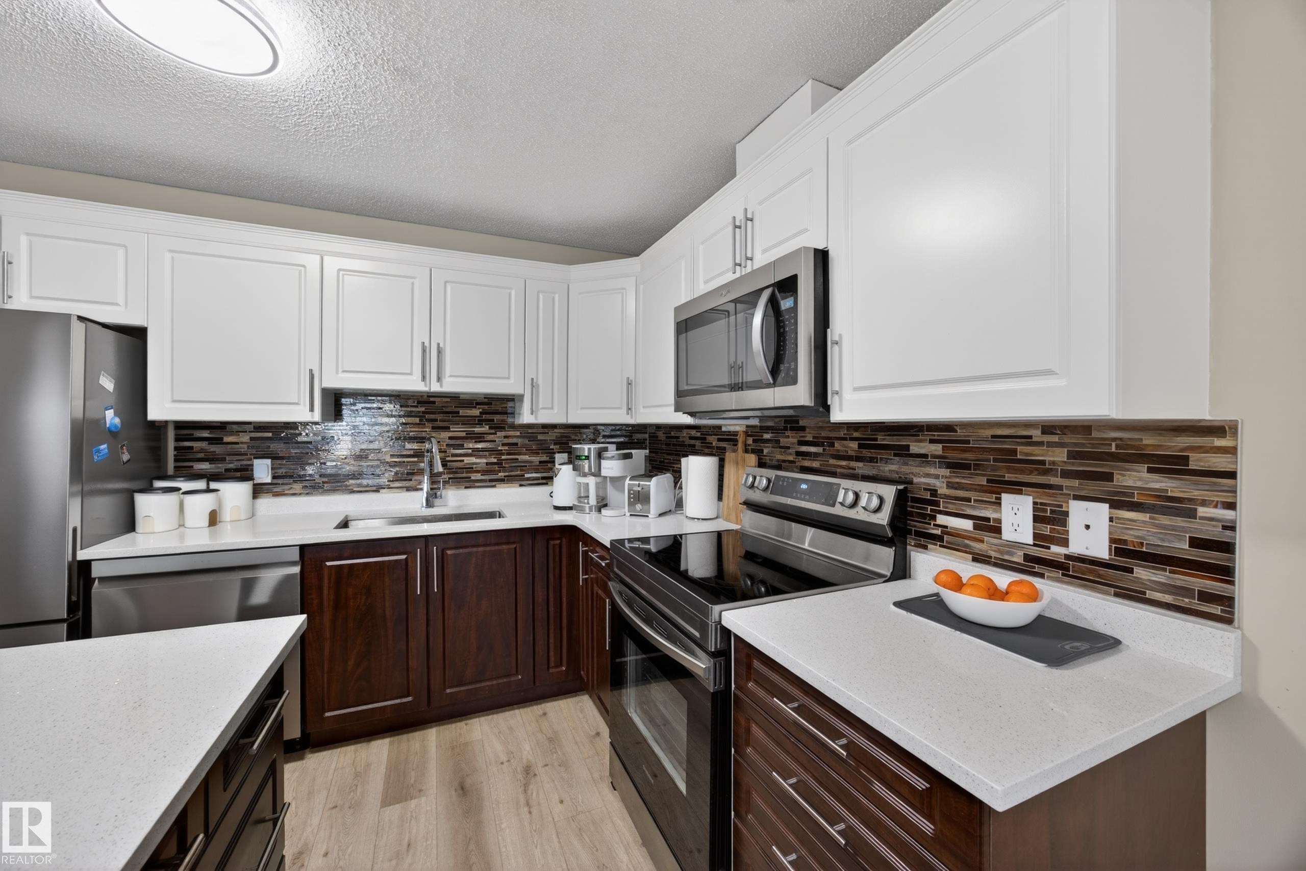 Modern kitchen featuring white upper cabinetry and dark wood-finish lower cabinetry - 138 16035 132 Street, Edmonton, AB