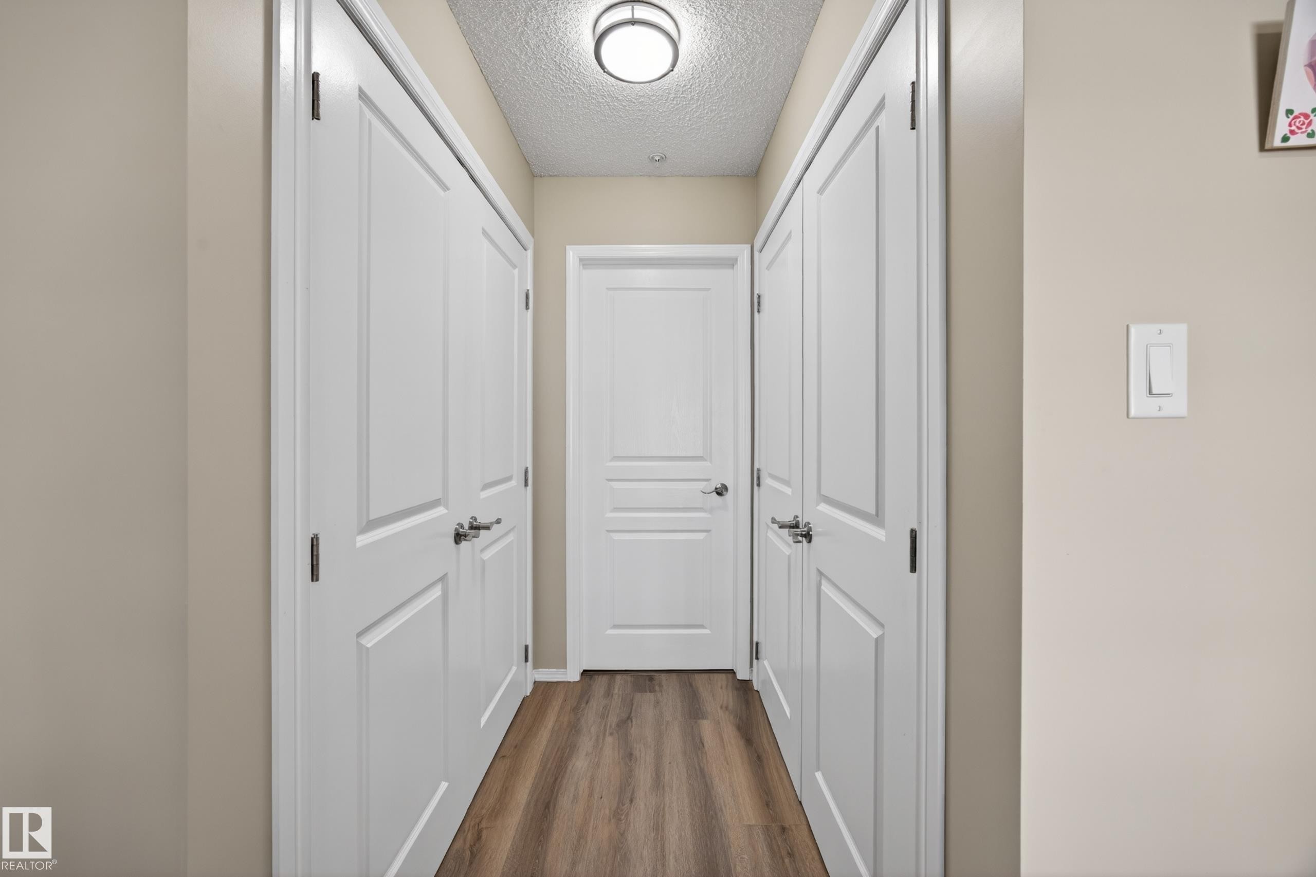 Hallway with wood-finish flooring, light tan wall color, and white trim - 138 16035 132 Street, Edmonton, AB