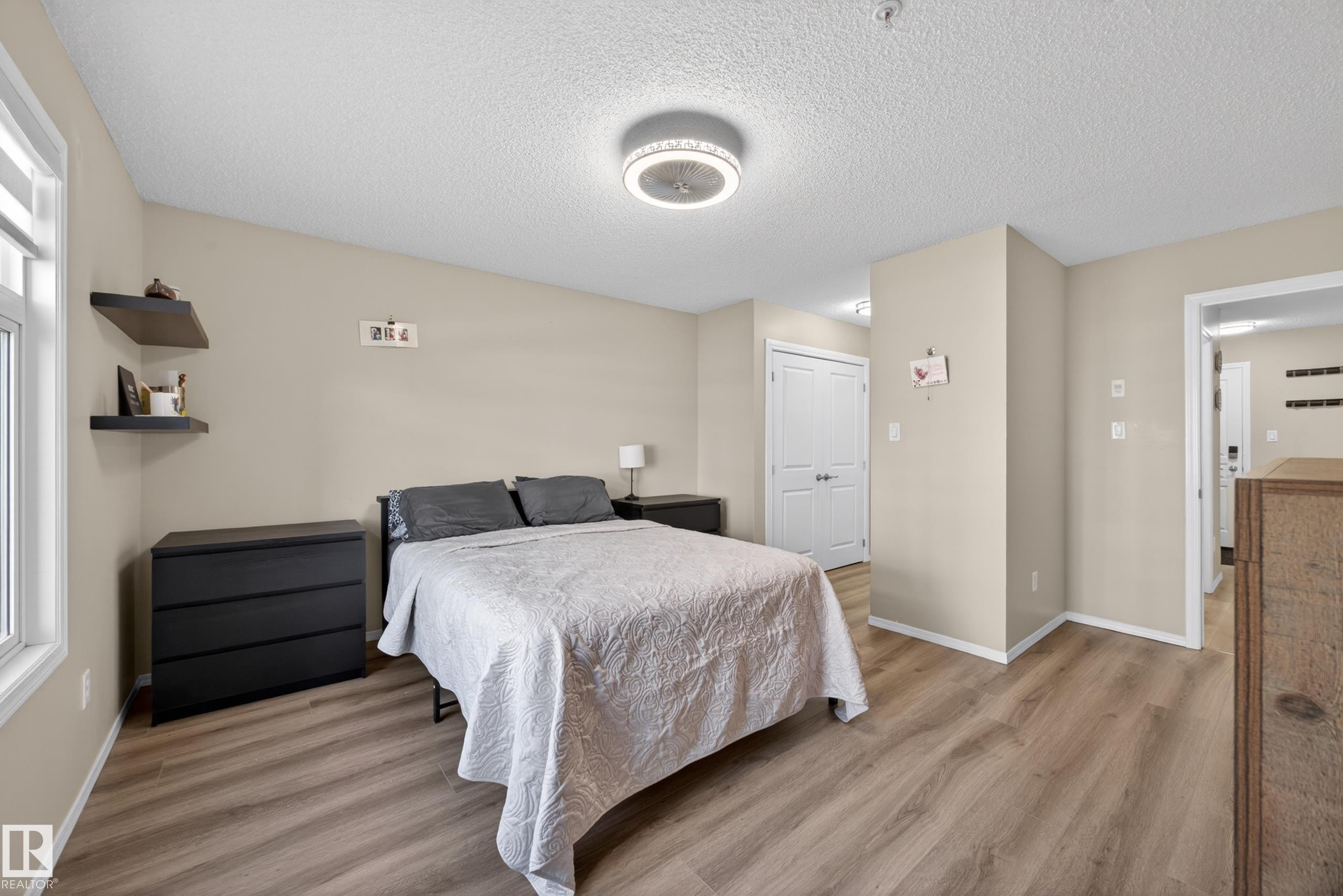 Bedroom featuring wood-finish flooring, neutral wall paint, and a white window frame - 138 16035 132 Street, Edmonton, AB
