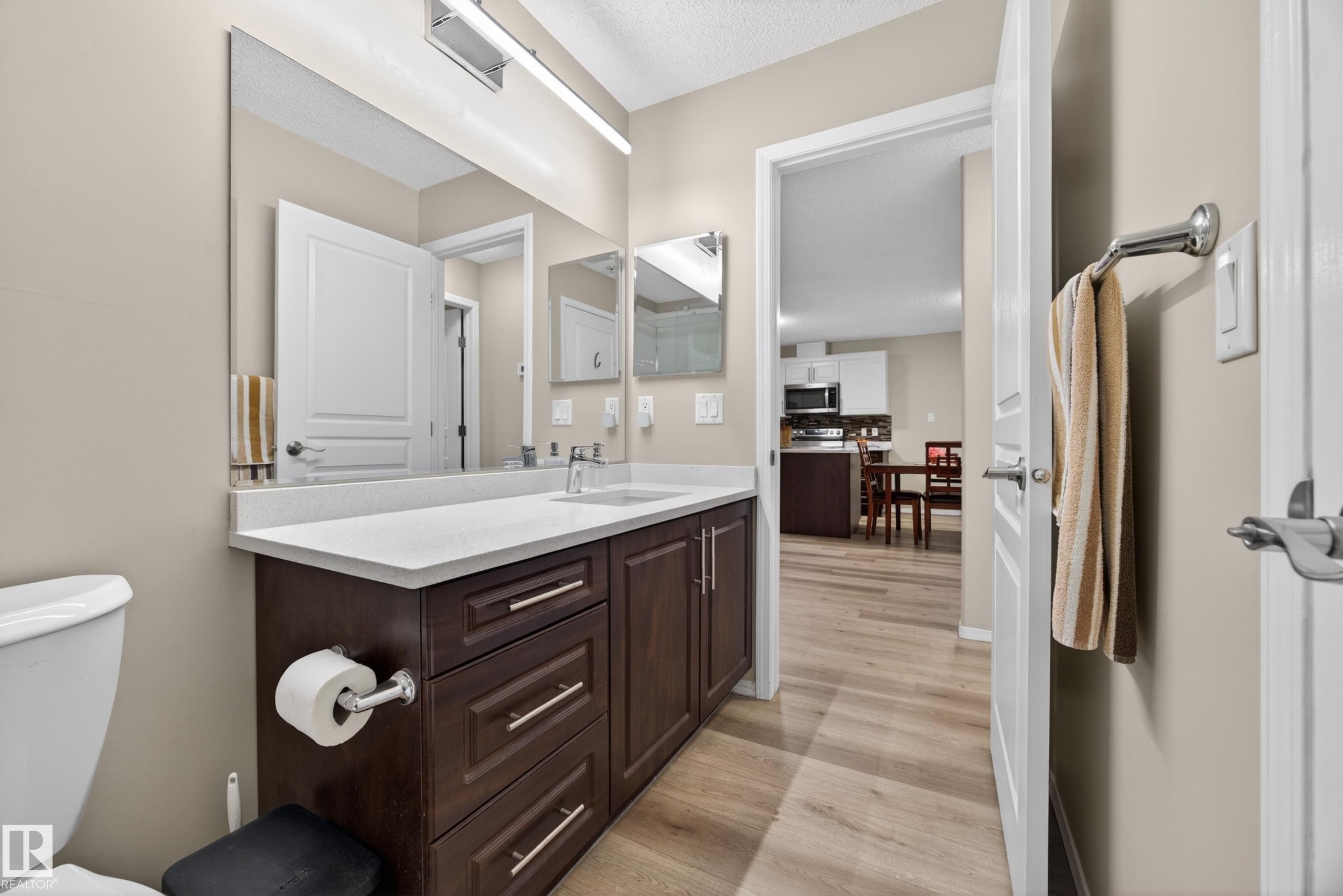 Bathroom featuring a dark wood-finish vanity with a light countertop, a rectangular sink, and a large wall-mounted mirror - 138 16035 132 Street, Edmonton, AB