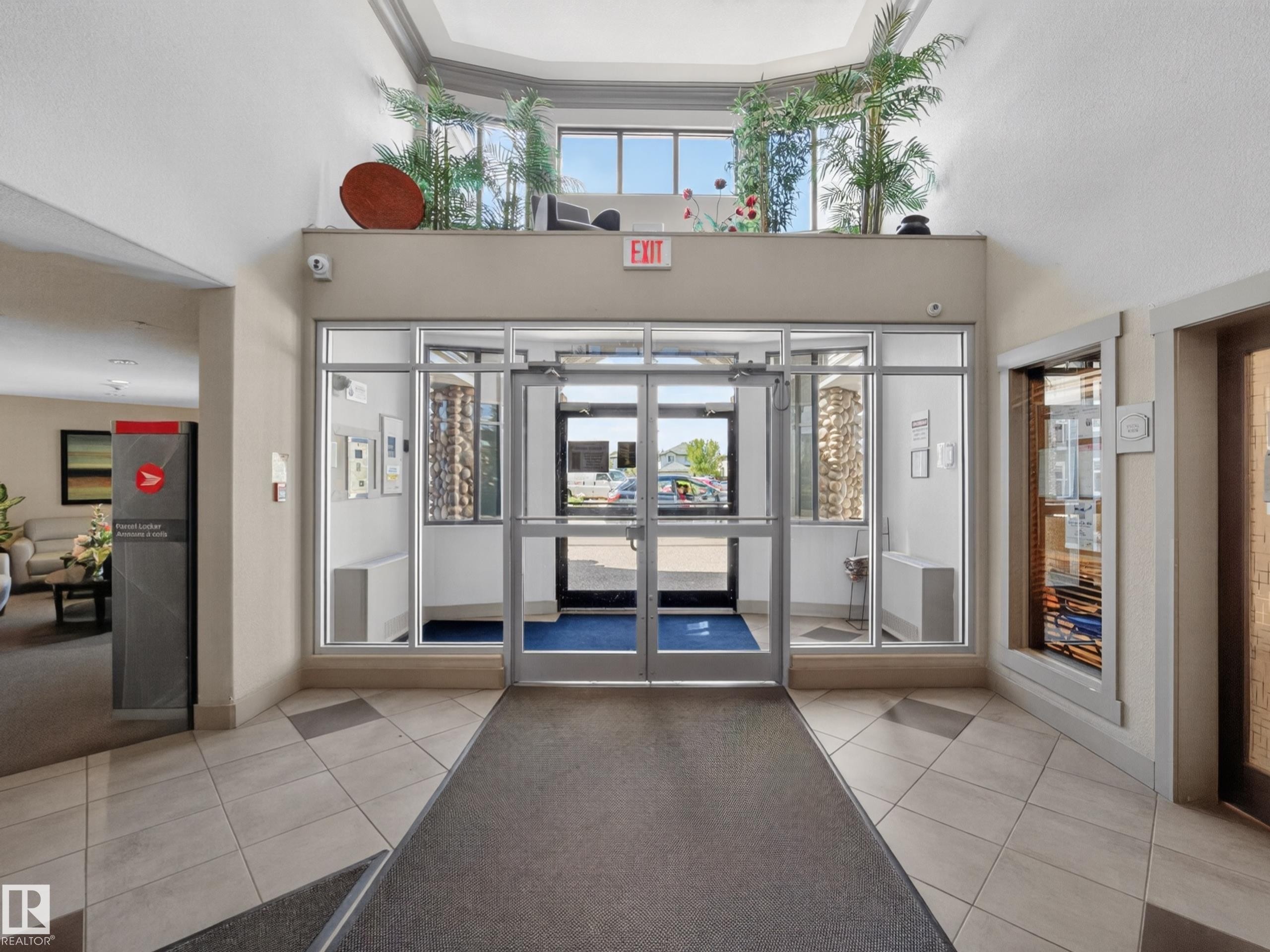 Foyer entrance featuring glass doors, tiled flooring, high ceilings, and an upper window shelf with decorative plants - 138 16035 132 Street, Edmonton, AB