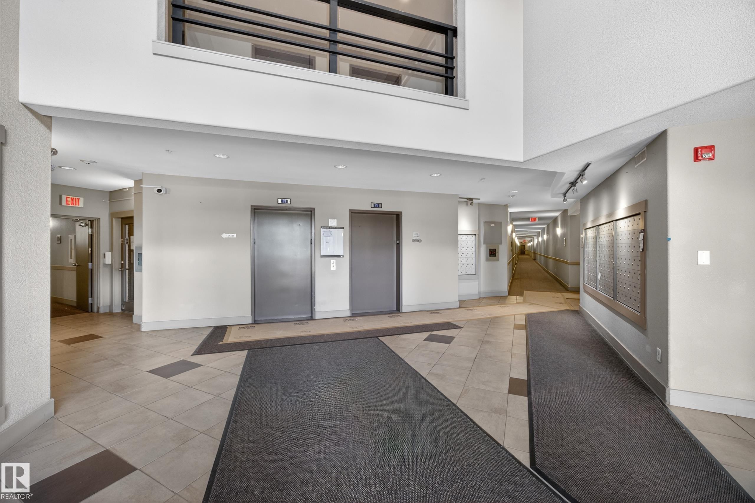 Building entrance featuring dual elevators with brushed metal doors, recessed overhead lighting, and neutral-toned floor tile - 138 16035 132 Street, Edmonton, AB