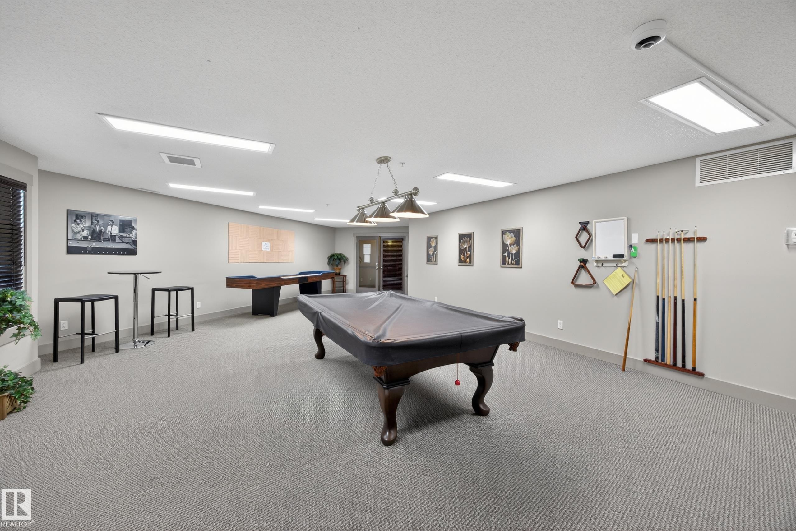 Spacious recreational room featuring two billiards tables, soft grey carpeting, and ample overhead lighting - 138 16035 132 Street, Edmonton, AB