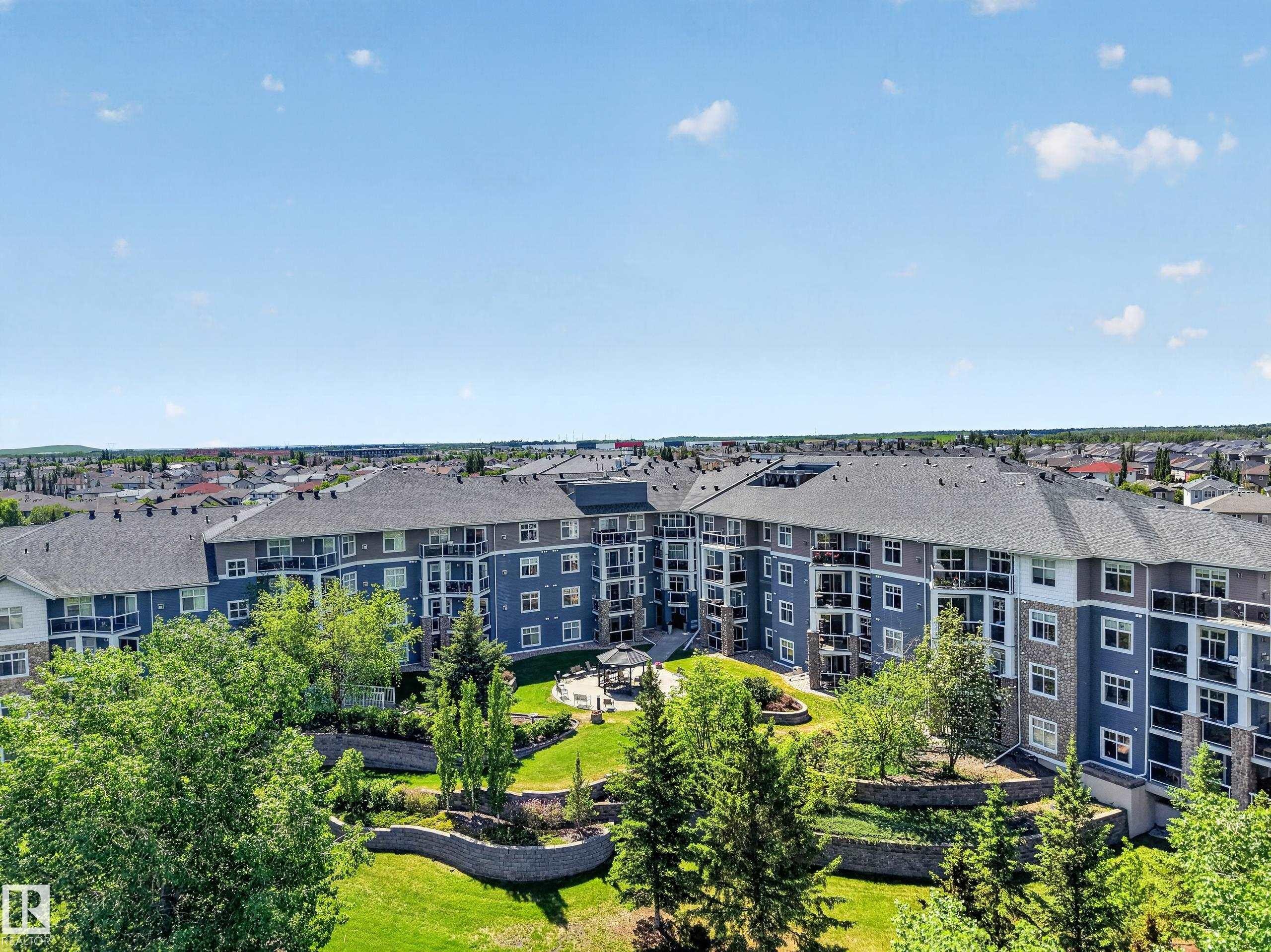 Multi-story residential complex featuring blue and gray siding with stone accents - 138 16035 132 Street, Edmonton, AB
