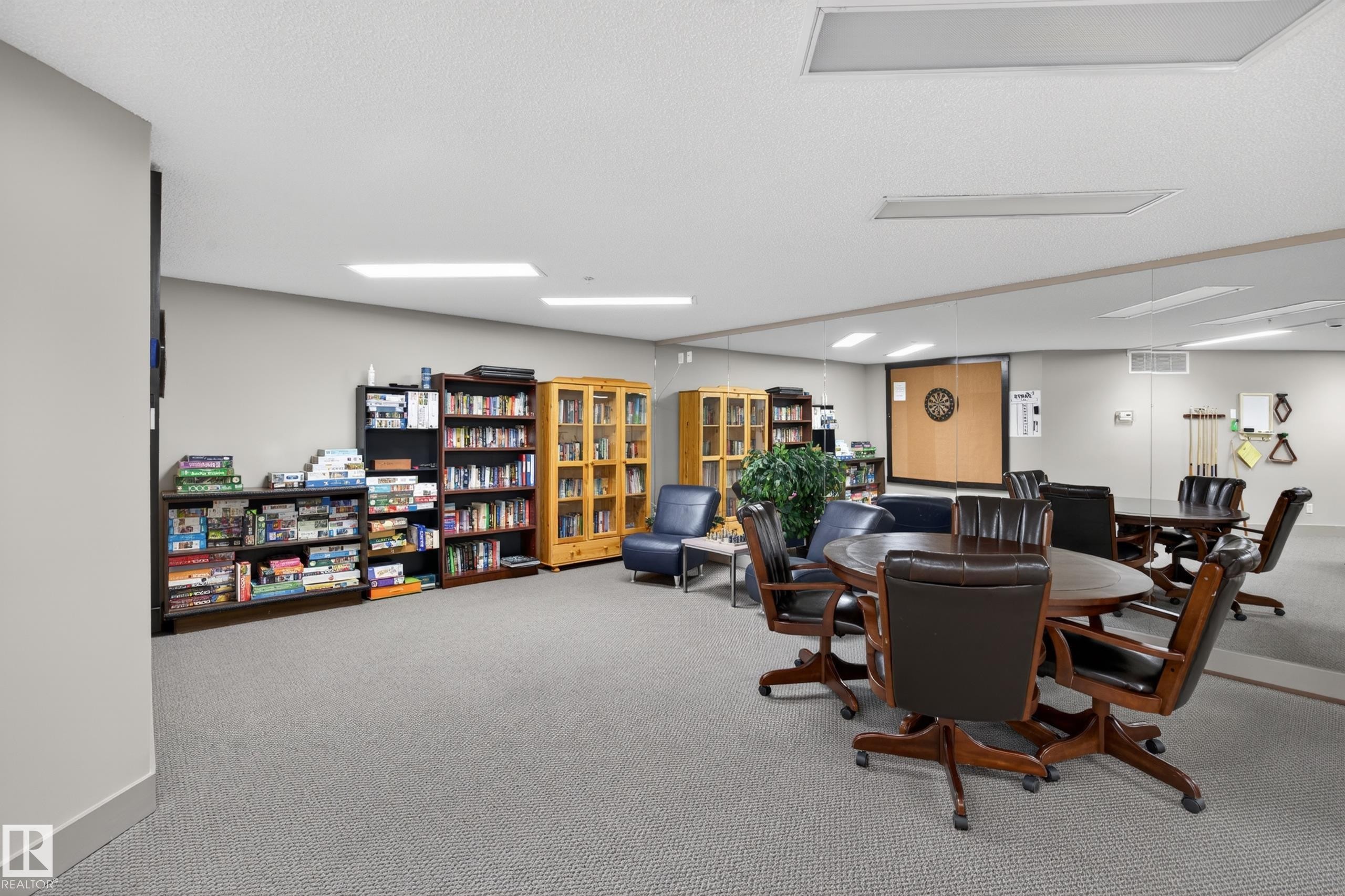 Recreation room featuring carpeted flooring, recessed lighting, built-in shelving, a mirrored wall, and a dartboard - 138 16035 132 Street, Edmonton, AB