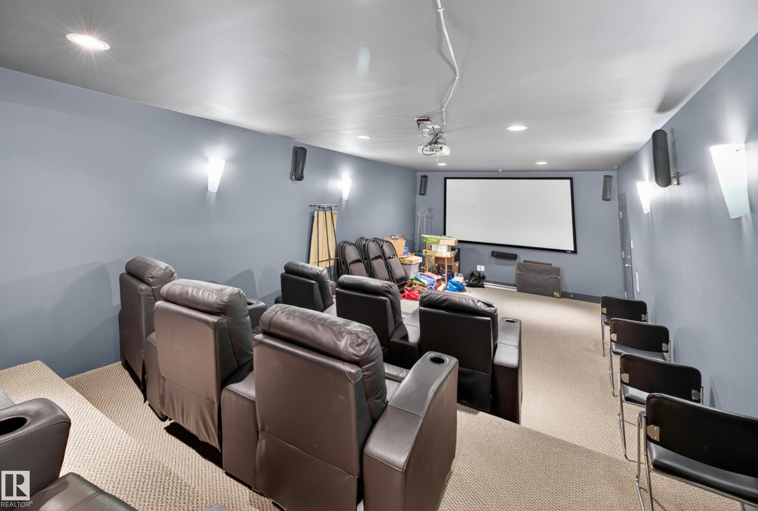Dedicated home theater featuring a large projection screen, mounted projector, recessed lighting, and wall sconces - 138 16035 132 Street, Edmonton, AB