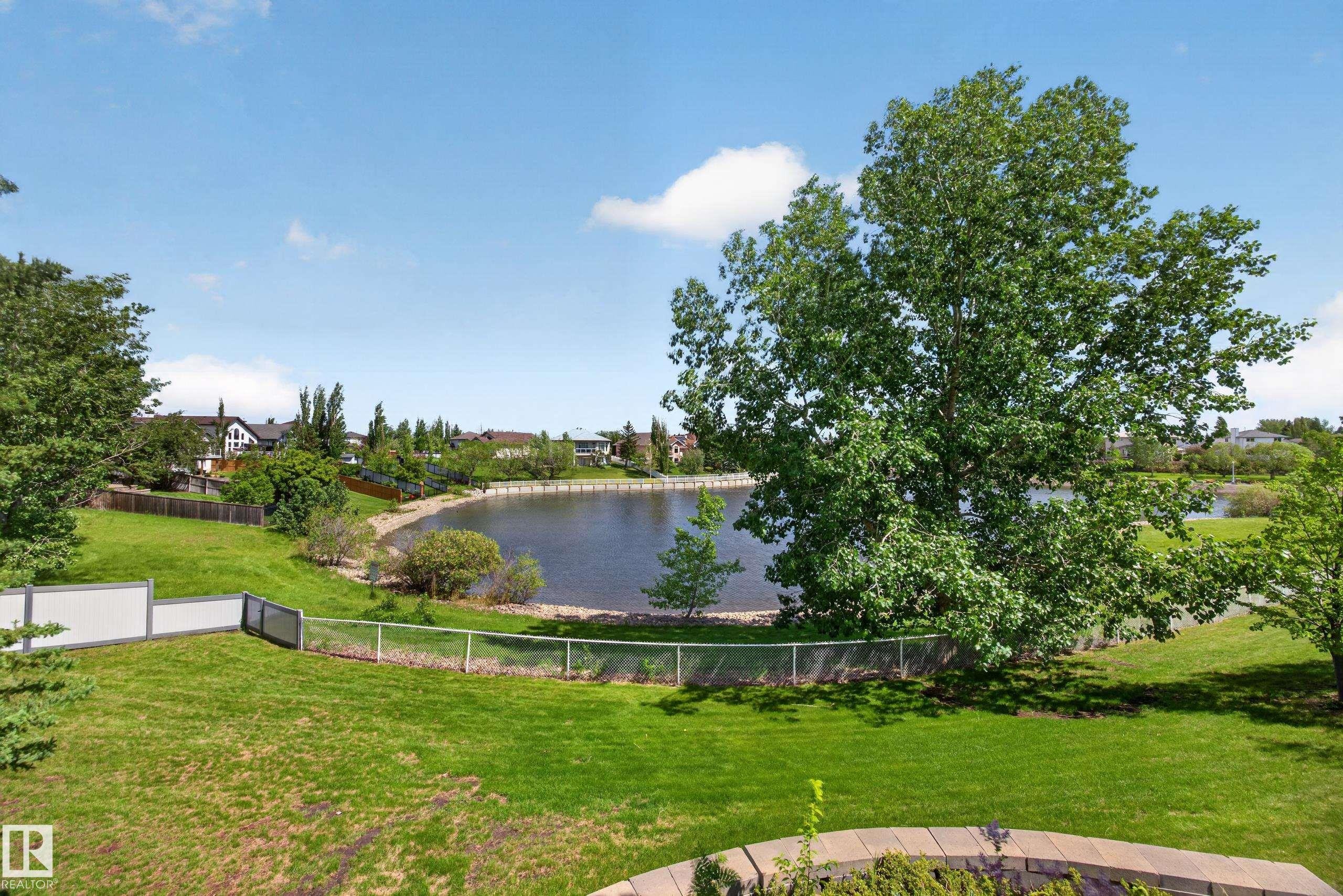 Expansive green lawn with mature trees and a stone-edged garden bed - 138 16035 132 Street, Edmonton, AB