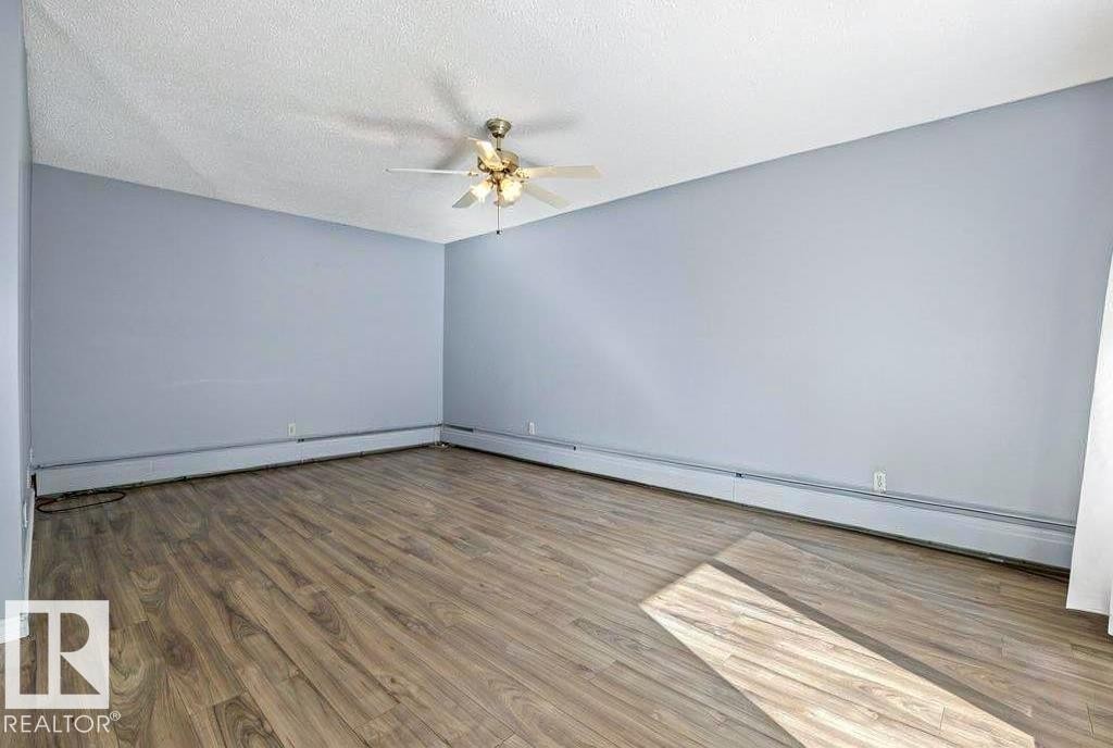 Wood-finish flooring, light blue wall paint, ceiling fan with integrated lighting, and perimeter heating - #1 13450 Fort Rd Nw, Edmonton, AB - Indoor Photo Showing Other Room