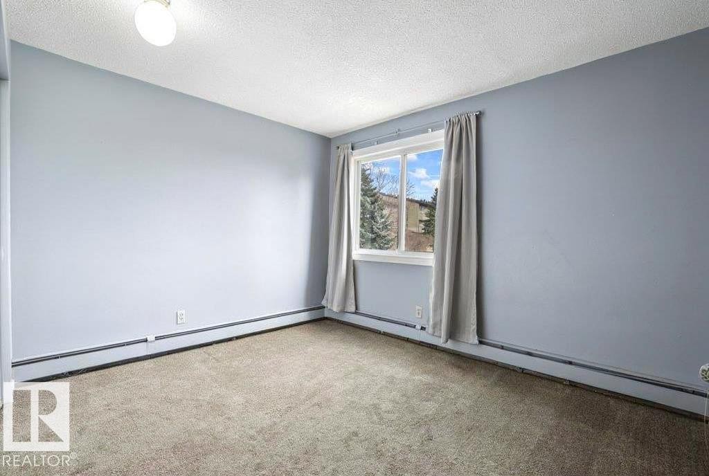 Carpeted flooring, single pane window, baseboard heating, ceiling-mounted light fixture, and light blue wall finish - #1 13450 Fort Rd Nw, Edmonton, AB - Indoor Photo Showing Other Room