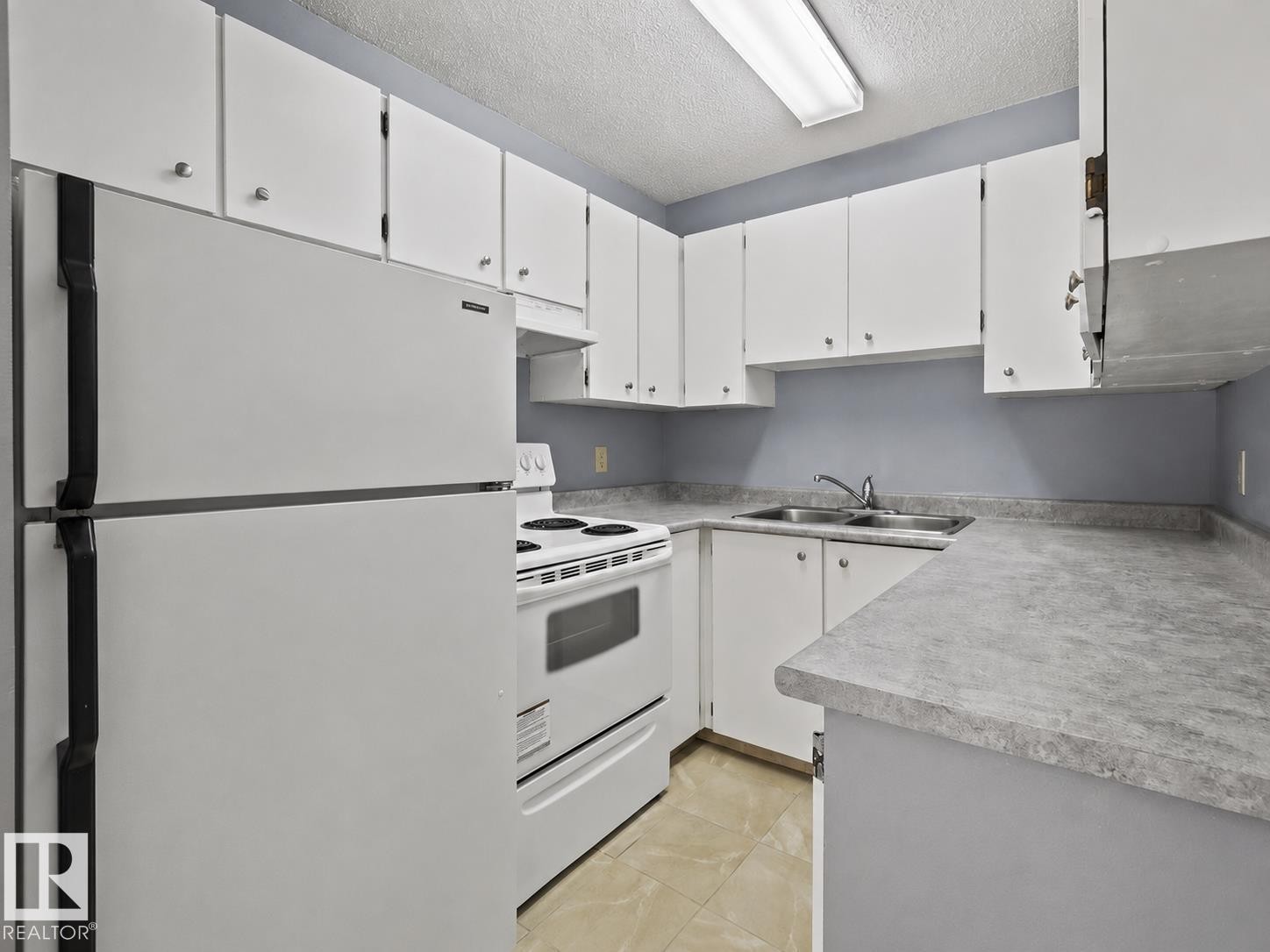 White upper and lower cabinetry, dual basin stainless steel sink, electric range, refrigerator, and tiled flooring - #1 13450 Fort Rd Nw, Edmonton, AB - Indoor Photo Showing Kitchen With Double Sink