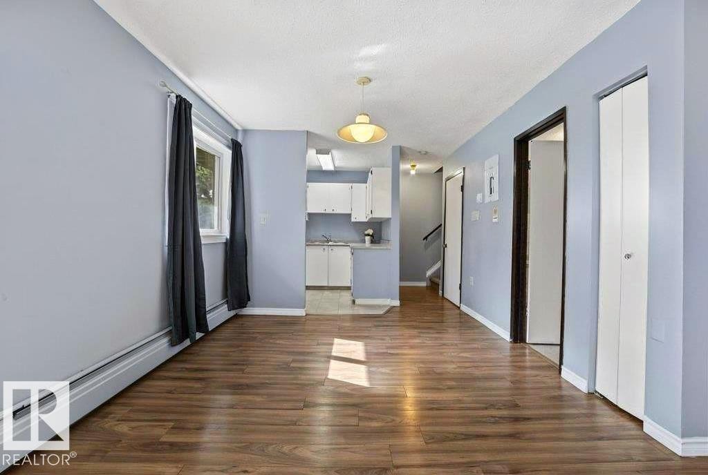 Wood-finish flooring throughout, light blue wall paint, white trim, and a window with a white frame - #1 13450 Fort Rd Nw, Edmonton, AB - Indoor Photo Showing Other Room