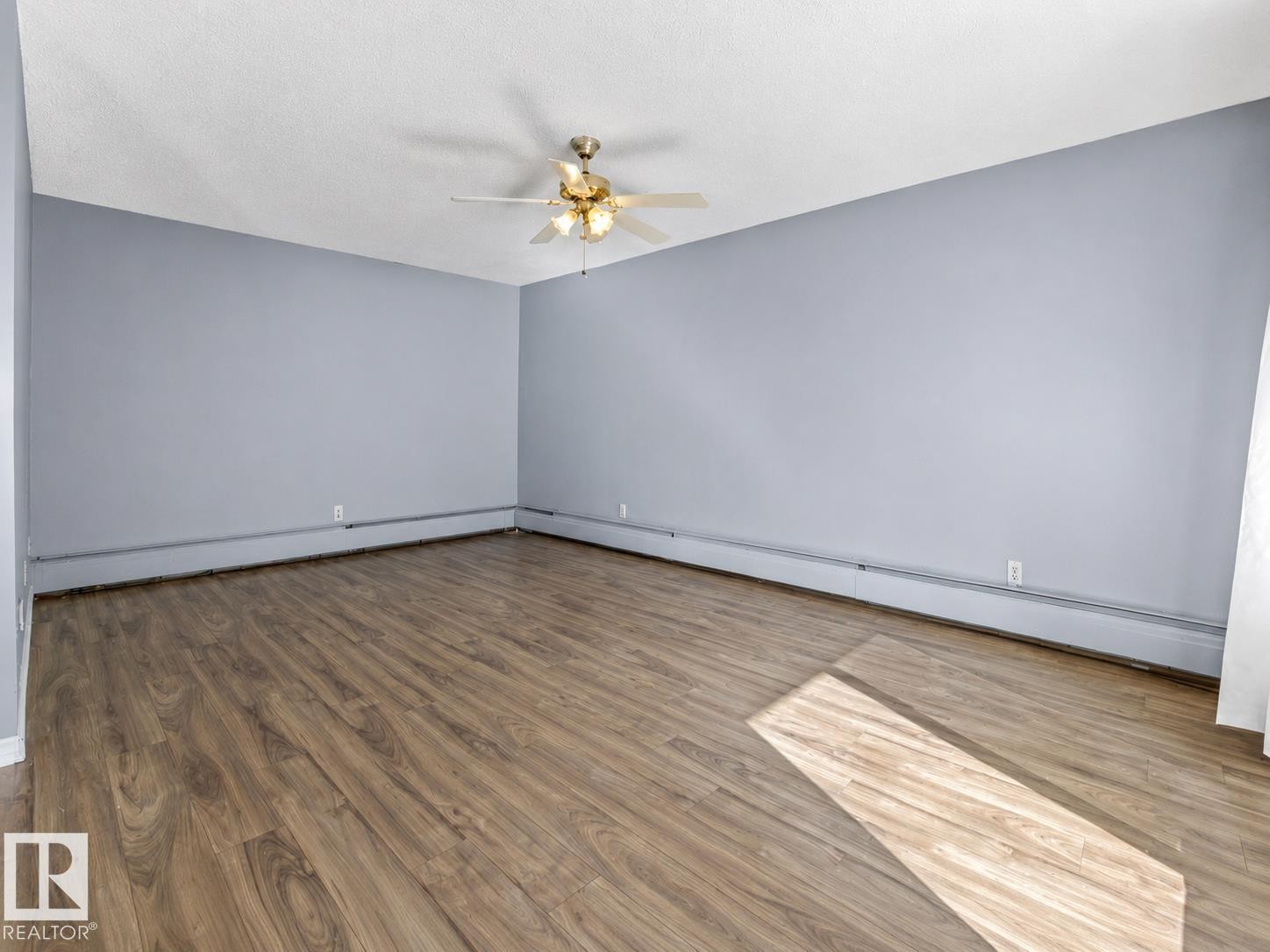 Wood-finish flooring, light blue walls, and a ceiling-mounted fan fixture - #1 13450 Fort Rd Nw, Edmonton, AB - Indoor Photo Showing Other Room